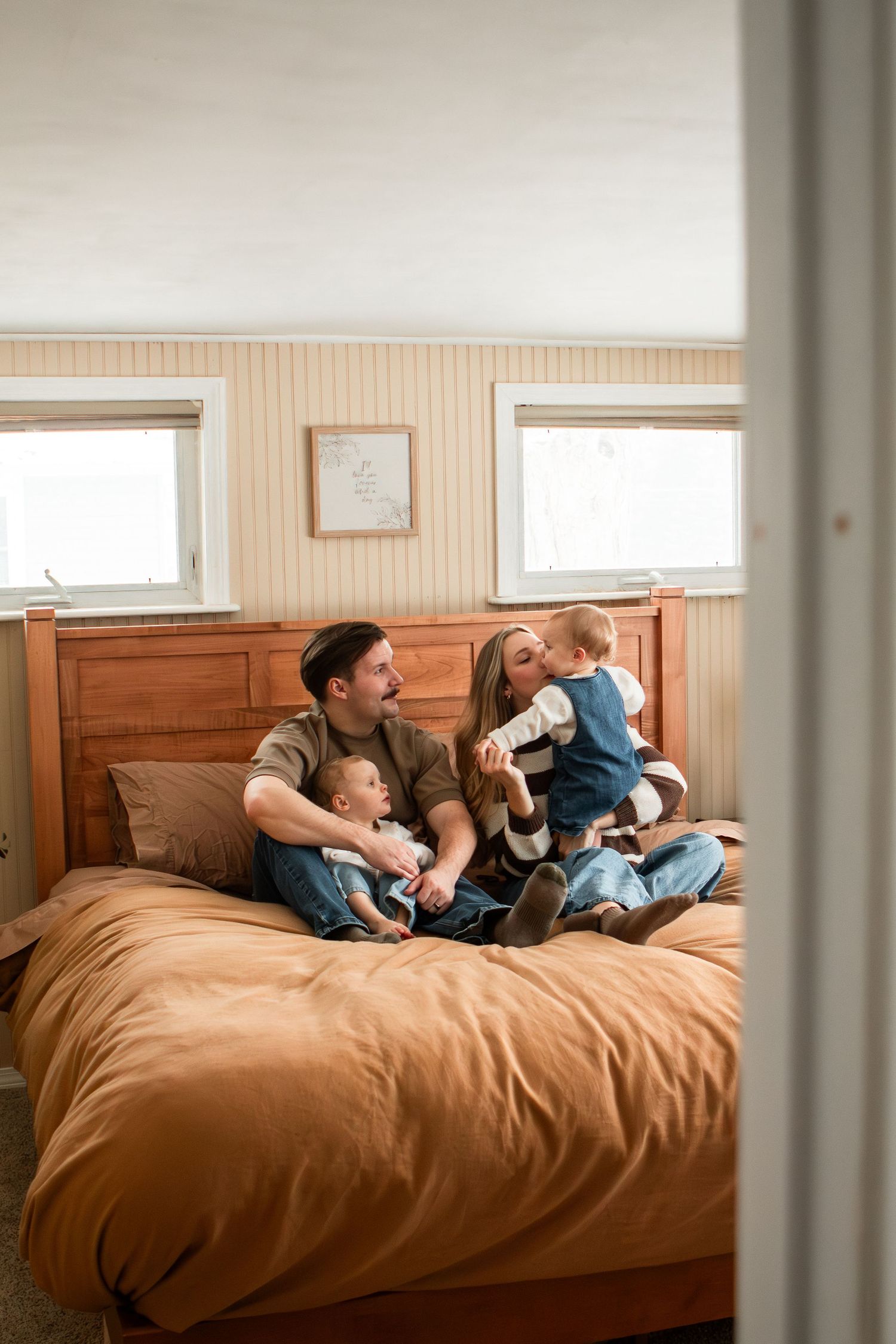 Family of four sitting on bed playing and snuggling in home in Columbus Ohio