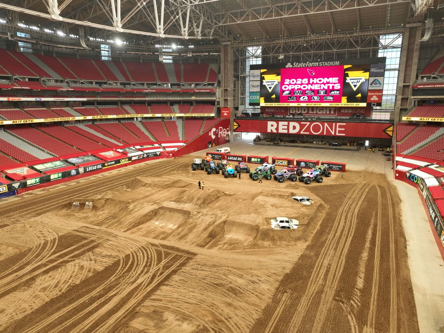 Monster truck rally setup inside a domed stadium with dirt track, jumps, and RedZone signage visible.