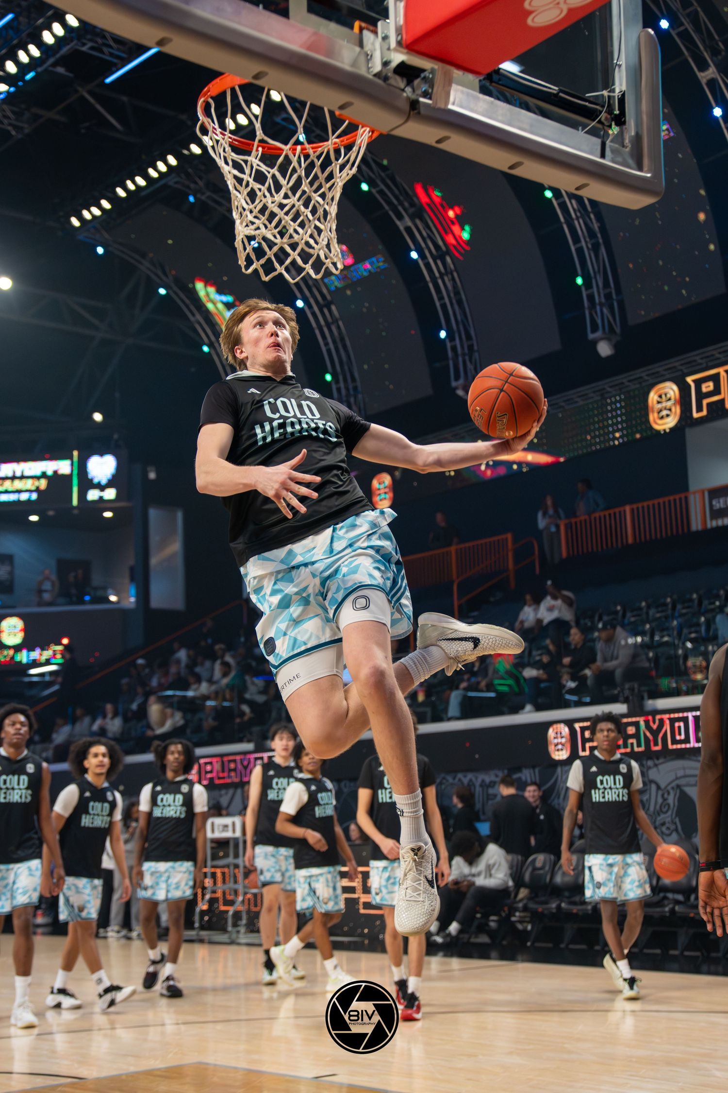 Young basketball player in Cold Hearts jersey leaping for a layup during warmups in an indoor arena.
