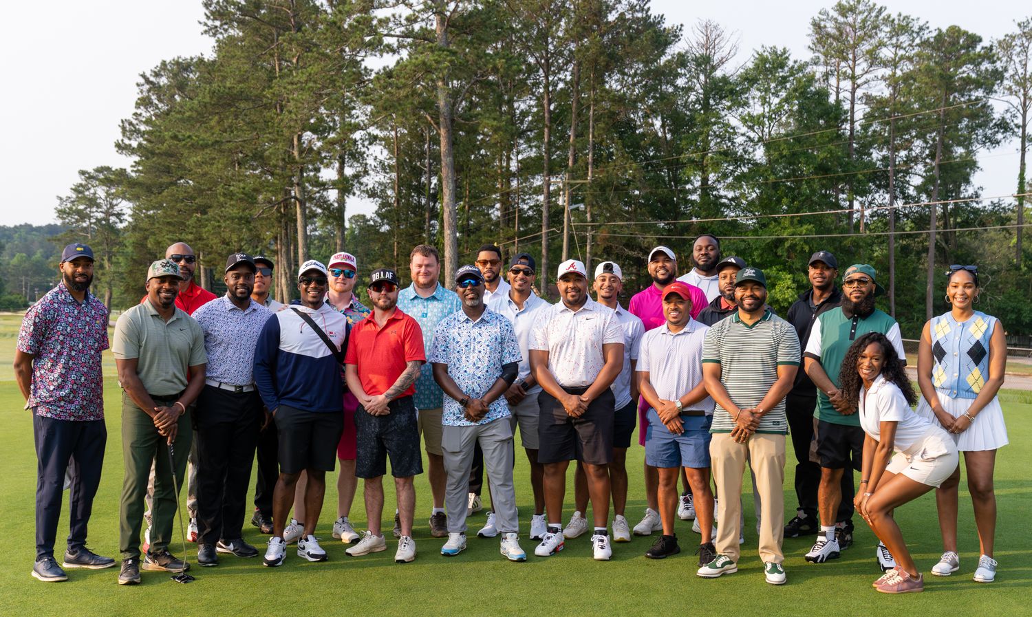 Diverse group of golfers posing together on a lush green golf course on a sunny day.