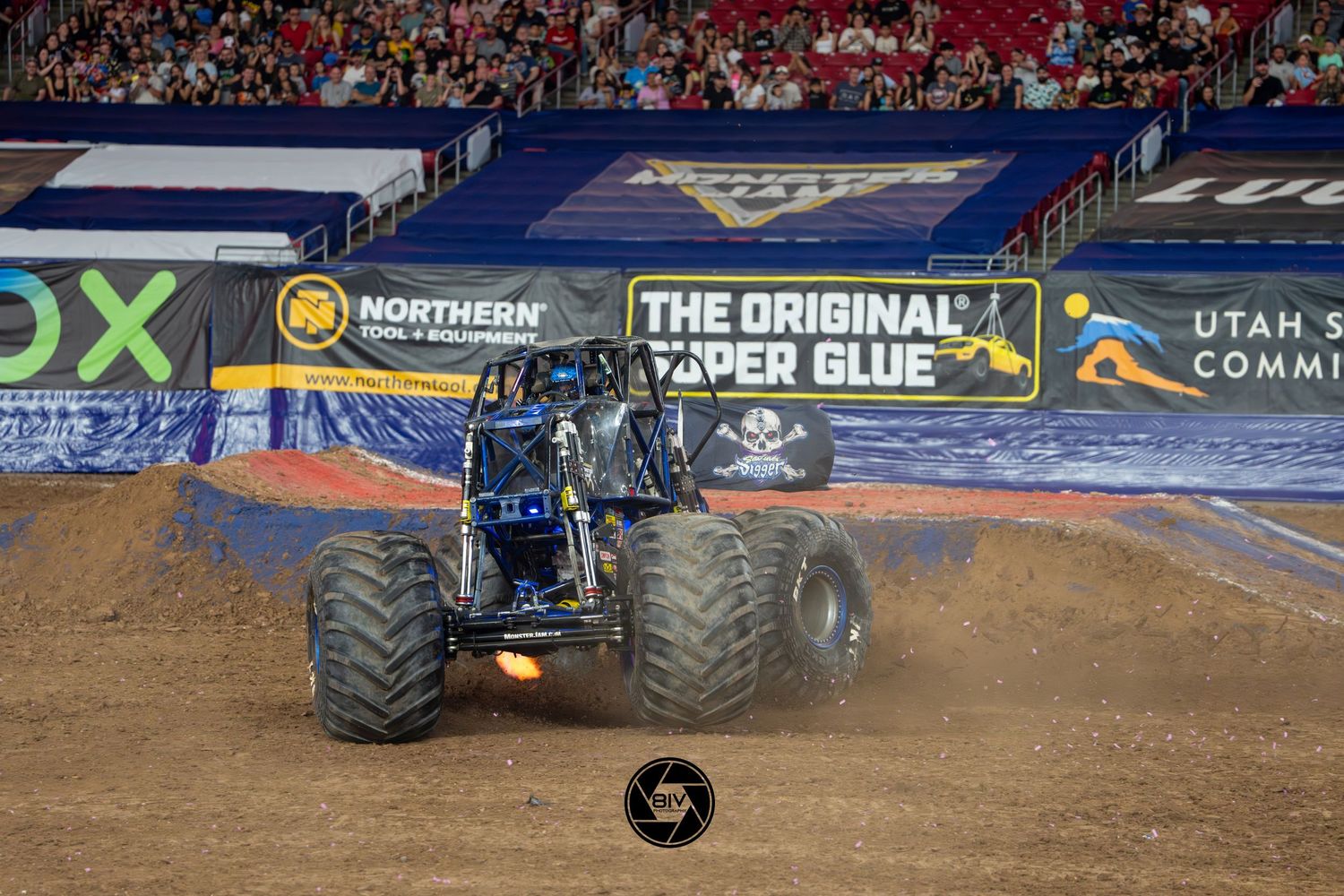 Son Uva Digger monster truck performing at Monster Jam stadium event on dirt track with sponsor banners visible in background.