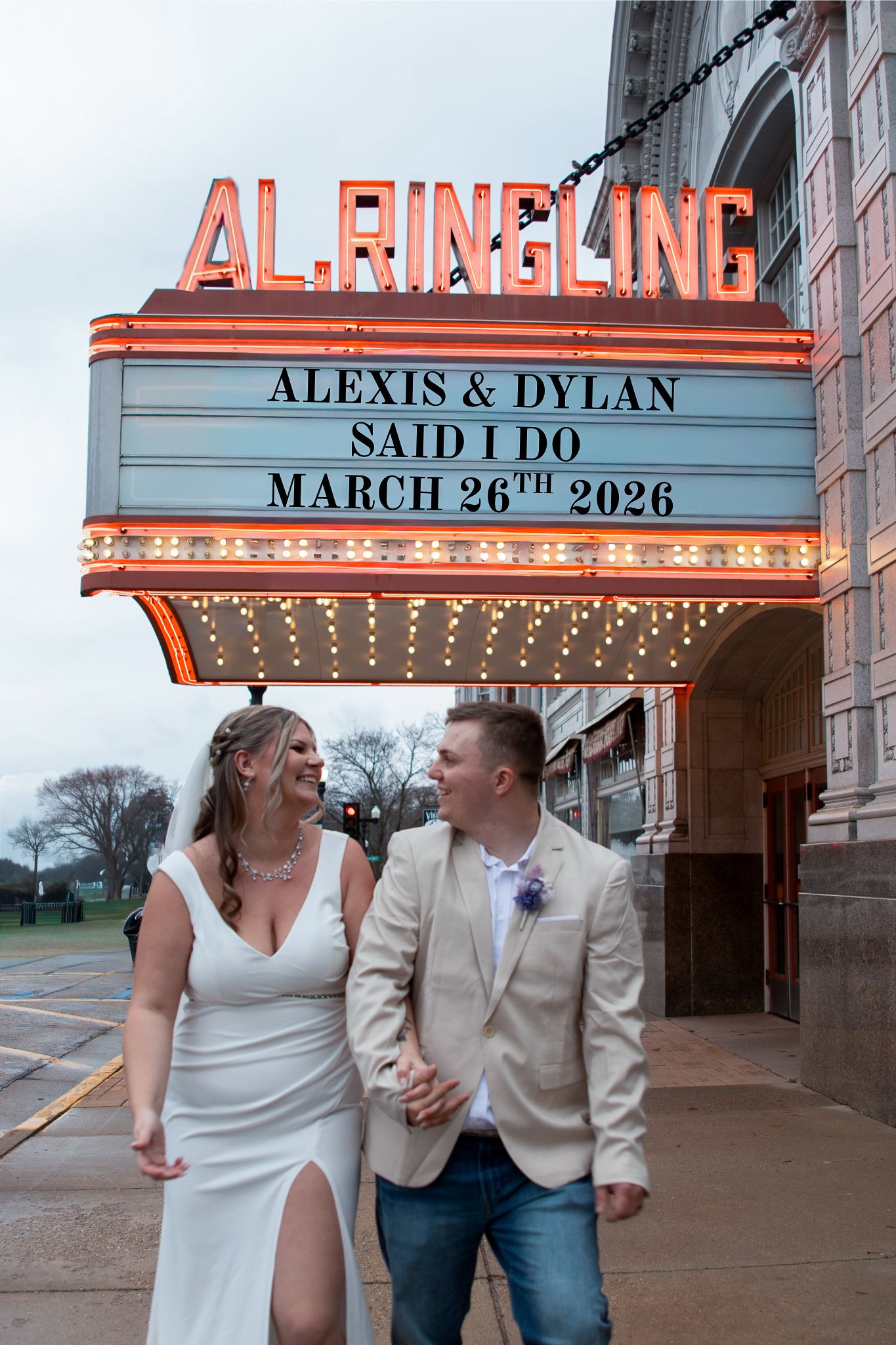 Bride and groom smile holding hands under the Al Ringling Theatre marquee announcing their March 26th 2026 wedding.