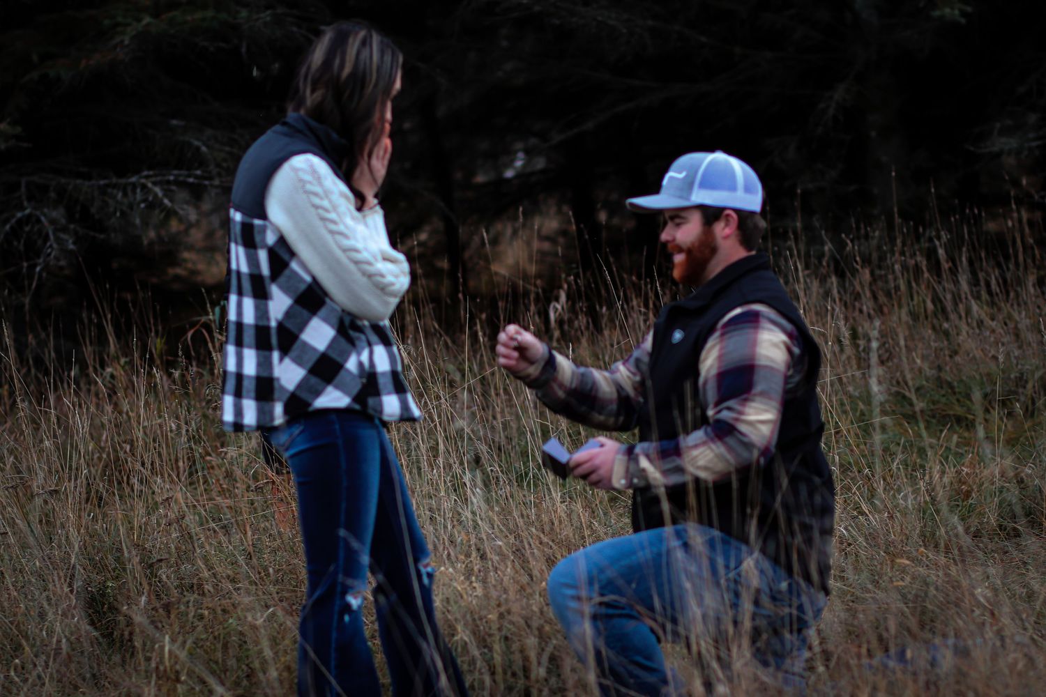 Man proposing to woman in a dark field at dusk.