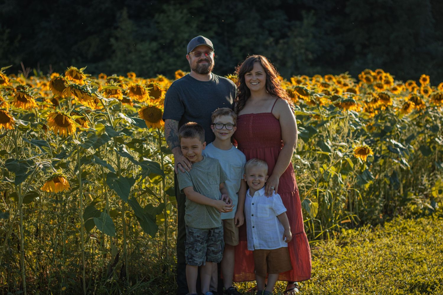 Family of five posing in a sunflower field during golden hour sunset photography session.