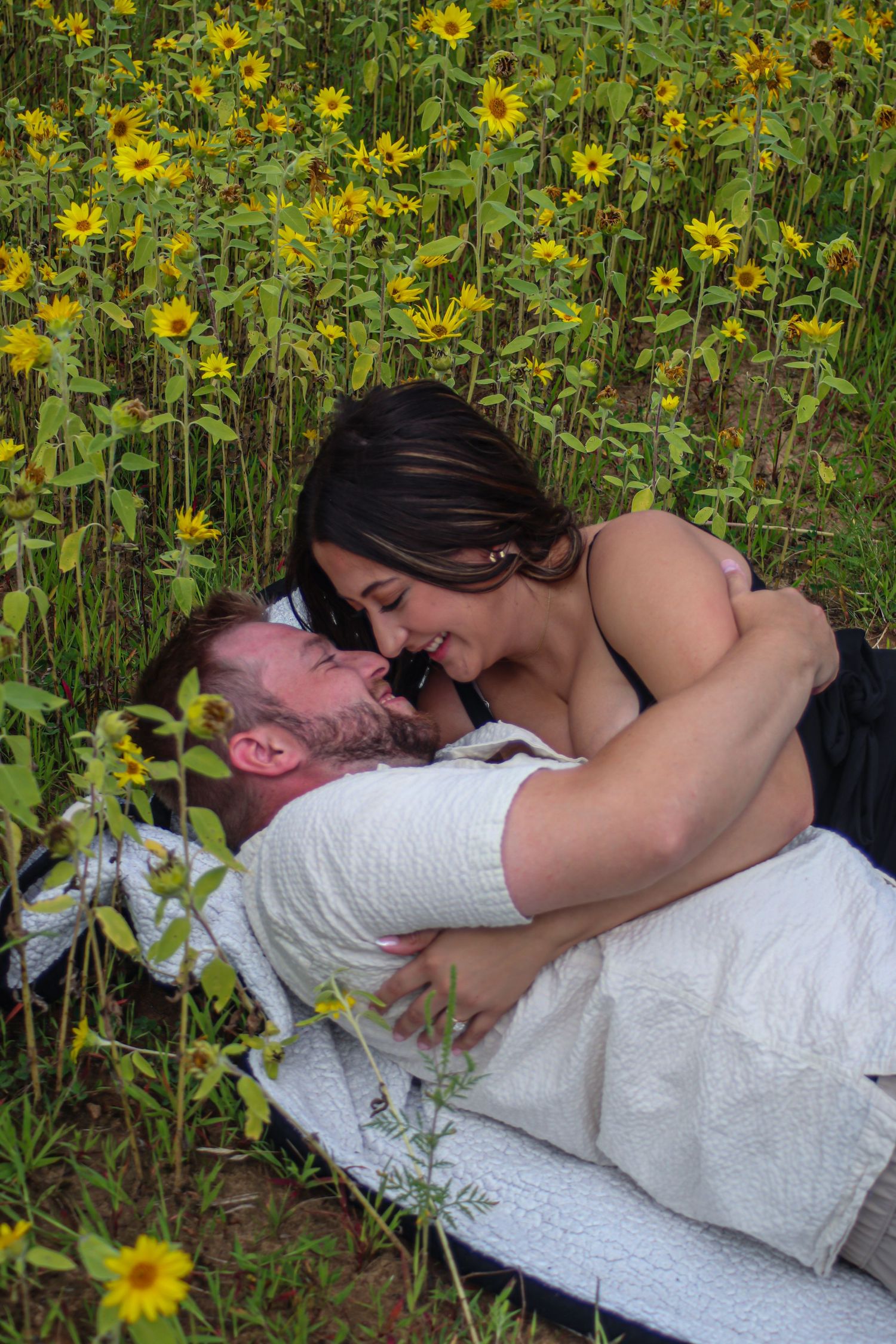 Couple sharing a romantic moment in a field of yellow flowers.