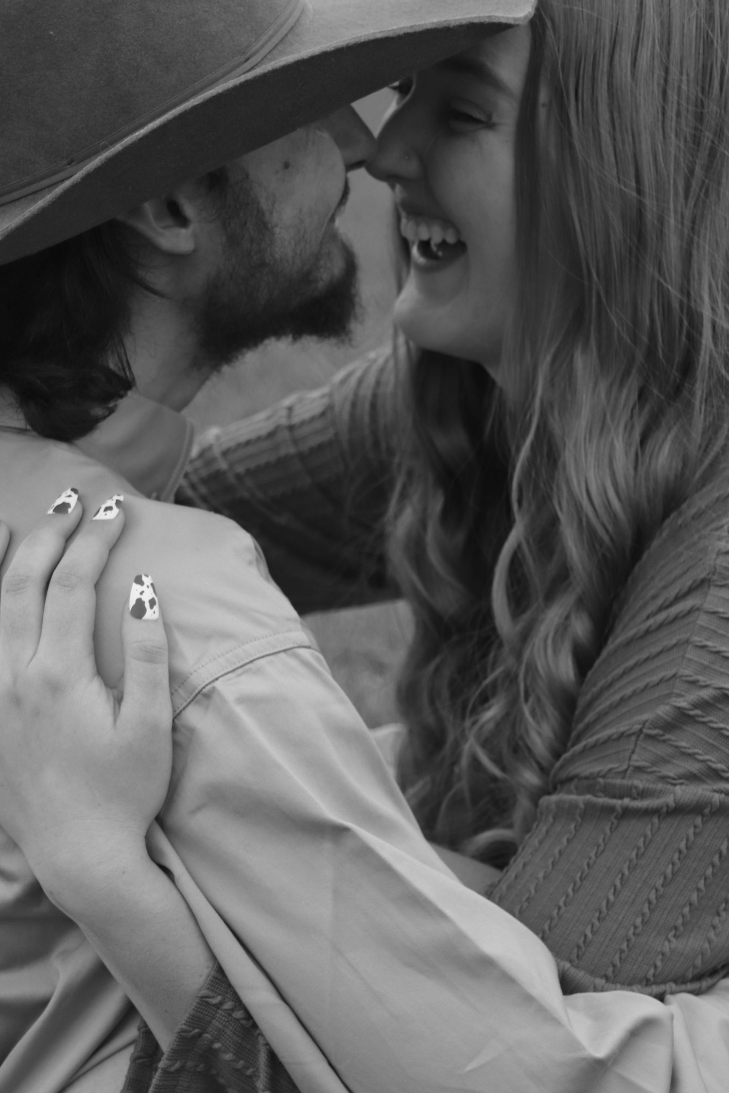 Black and white photo of couple laughing and almost kissing.