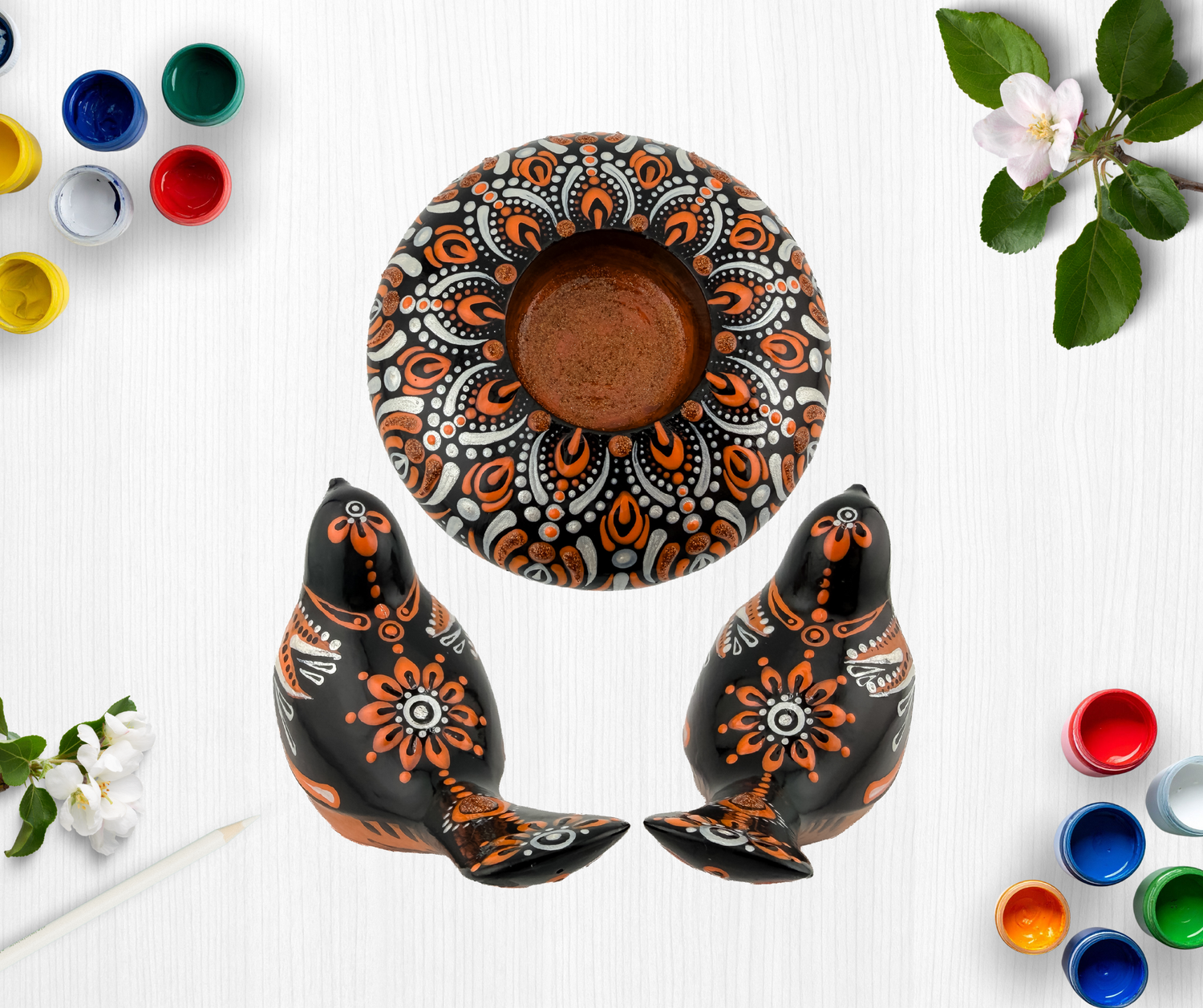 Hand-painted black ceramic pottery set with orange and white mandala floral designs, including a bowl and two bird figurines.