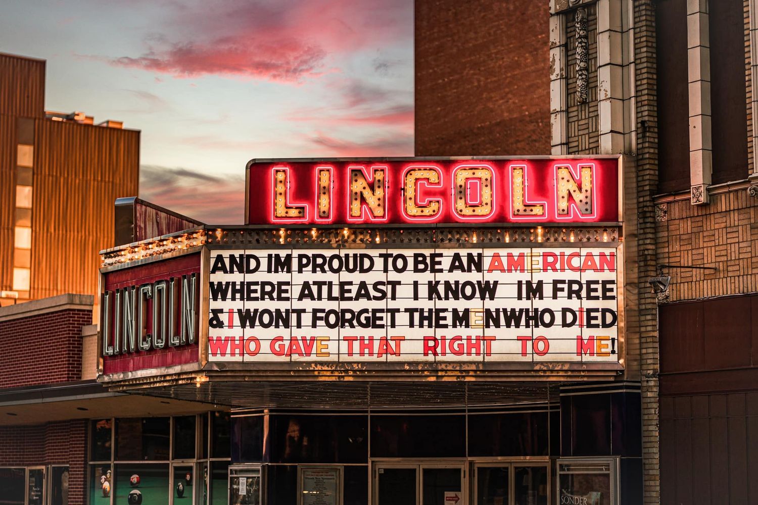 Lincoln Theatre marquee displaying patriotic lyrics at sunset in a classic American downtown district.