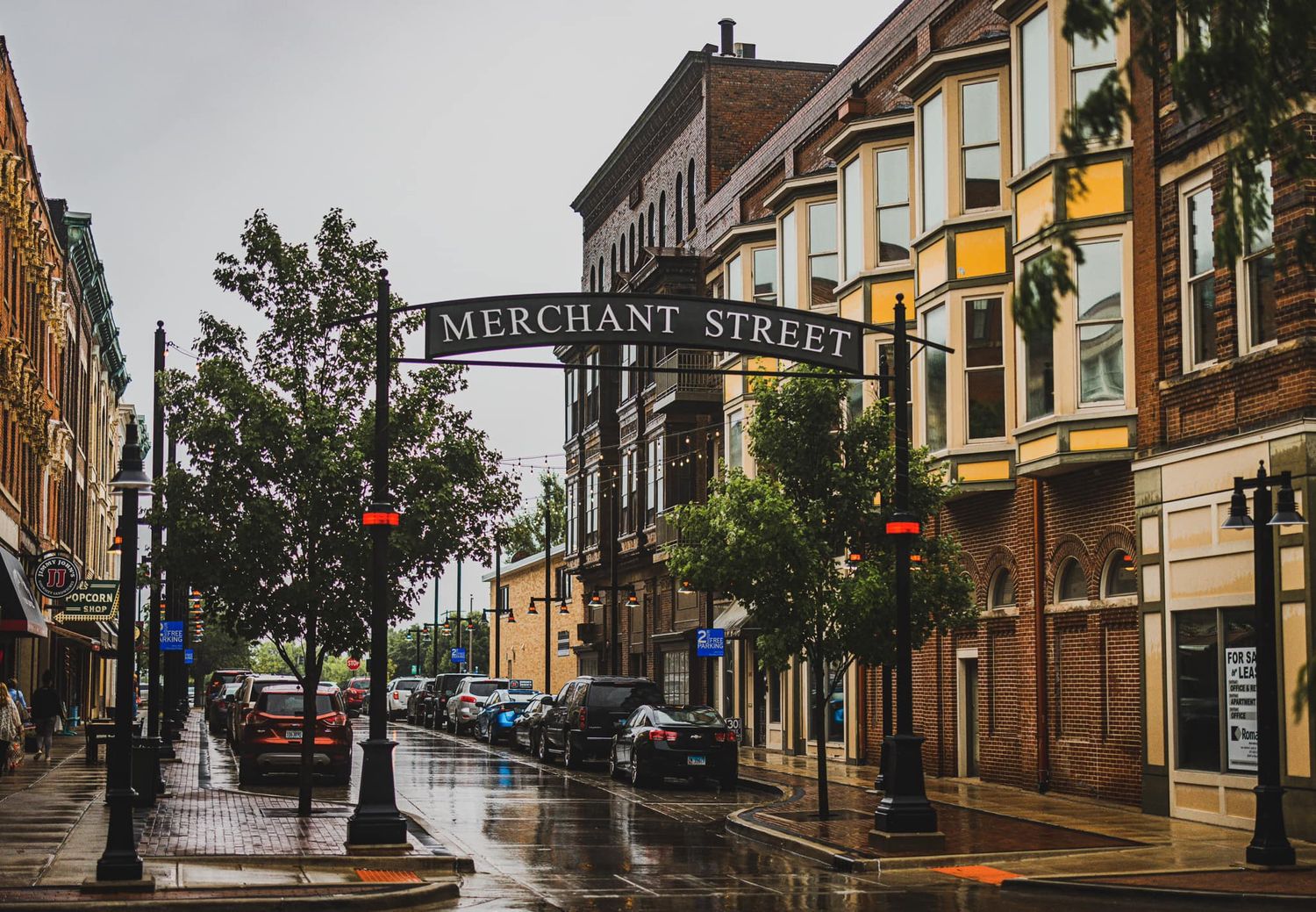 Rainy day on Merchant Street with wet reflections on pavement, lined with historic brick buildings and parked cars.