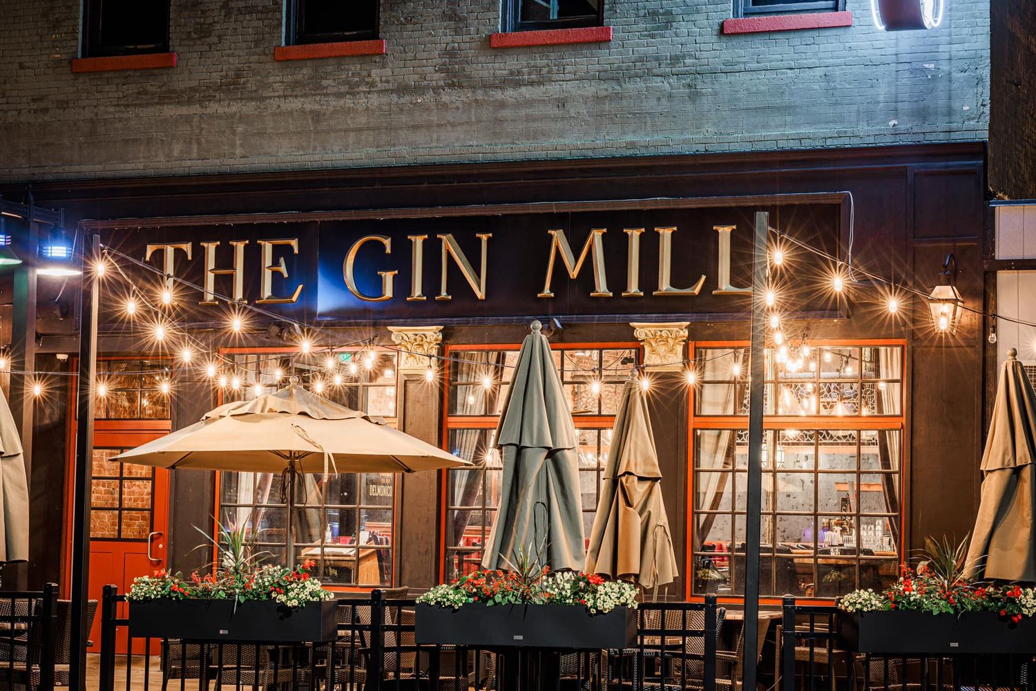 The Gin Mill restaurant outdoor patio with string lights, umbrellas, and tables on a cozy night.