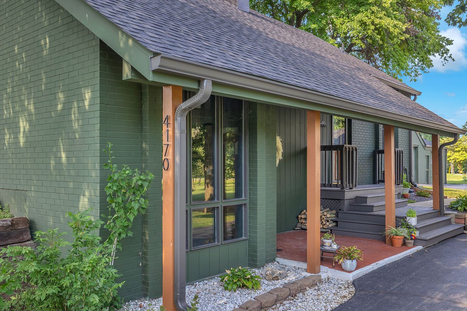Green craftsman home exterior with wood columns, black-framed windows, and address number 4170 on siding.