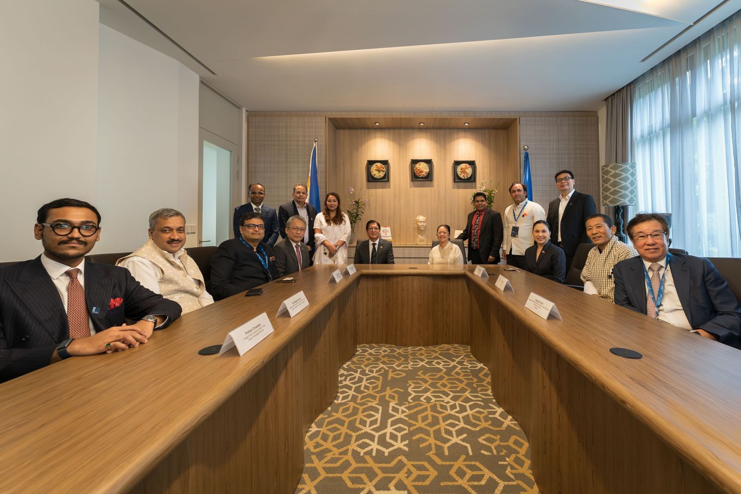 Group of diverse professionals seated around conference table in formal meeting room setting.