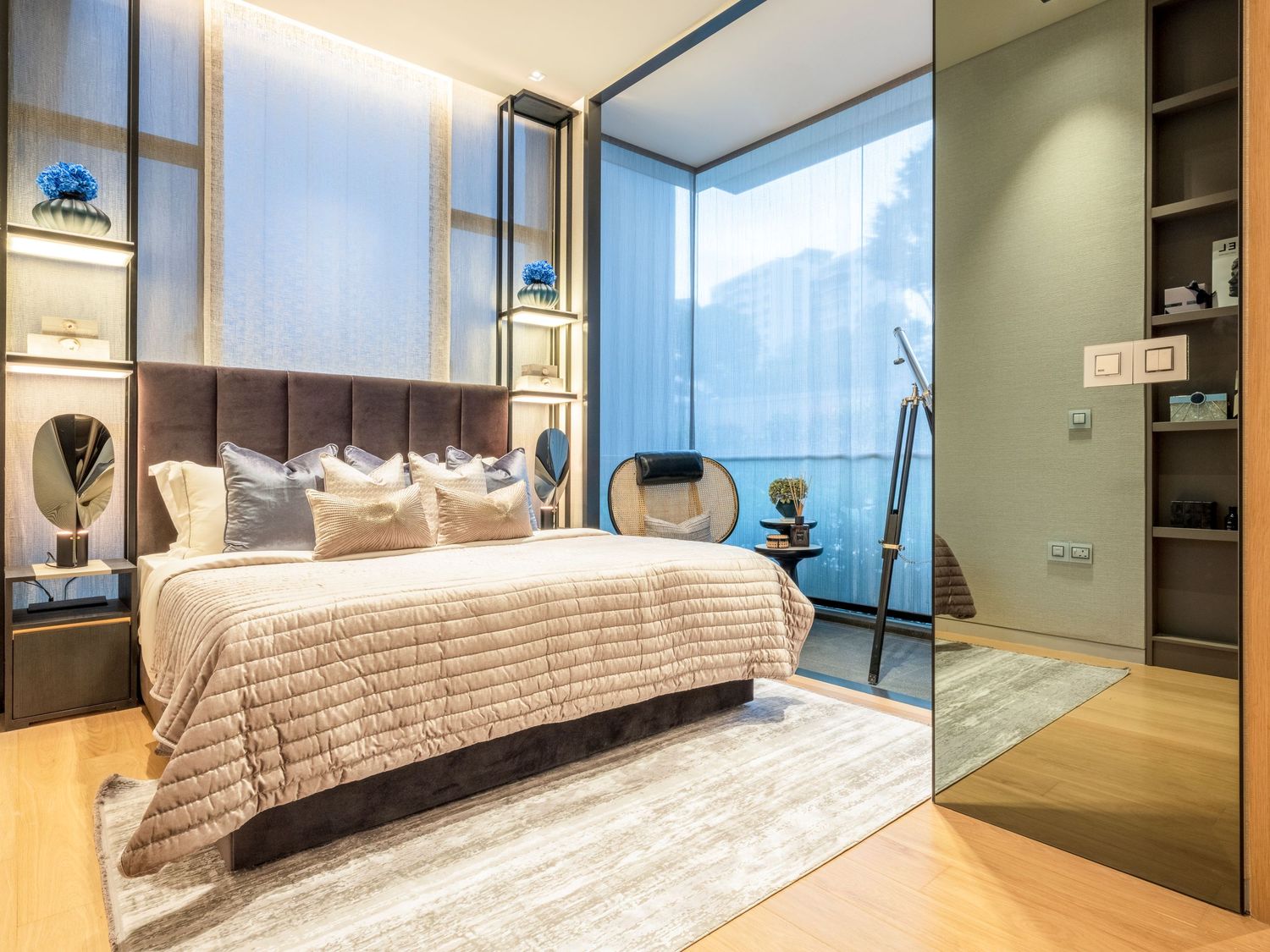 Luxurious modern bedroom with tufted headboard, neutral tones, floor-to-ceiling windows, and elegant built-in shelving.