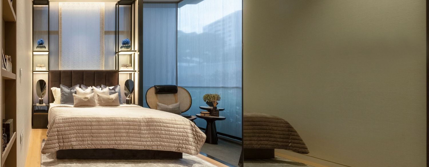 Contemporary bedroom with neutral tones, layered bedding, built-in shelves, and large window view.