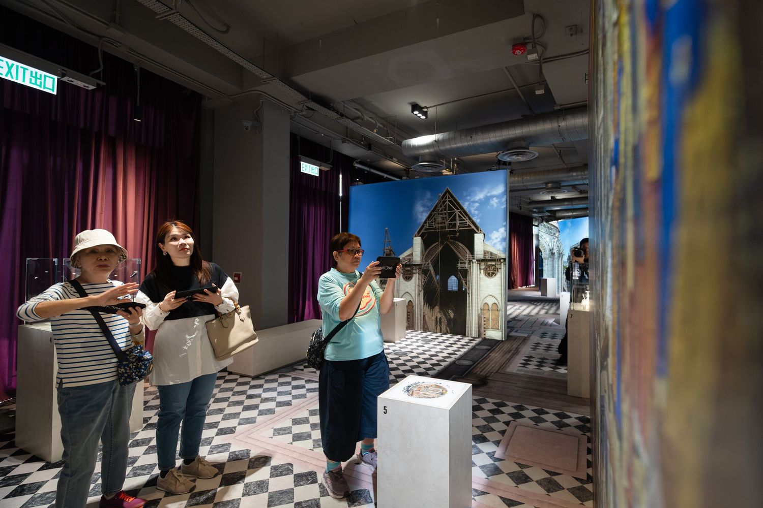 Visitors photograph vibrant Gothic cathedral artwork exhibits in a colorful interactive museum gallery.