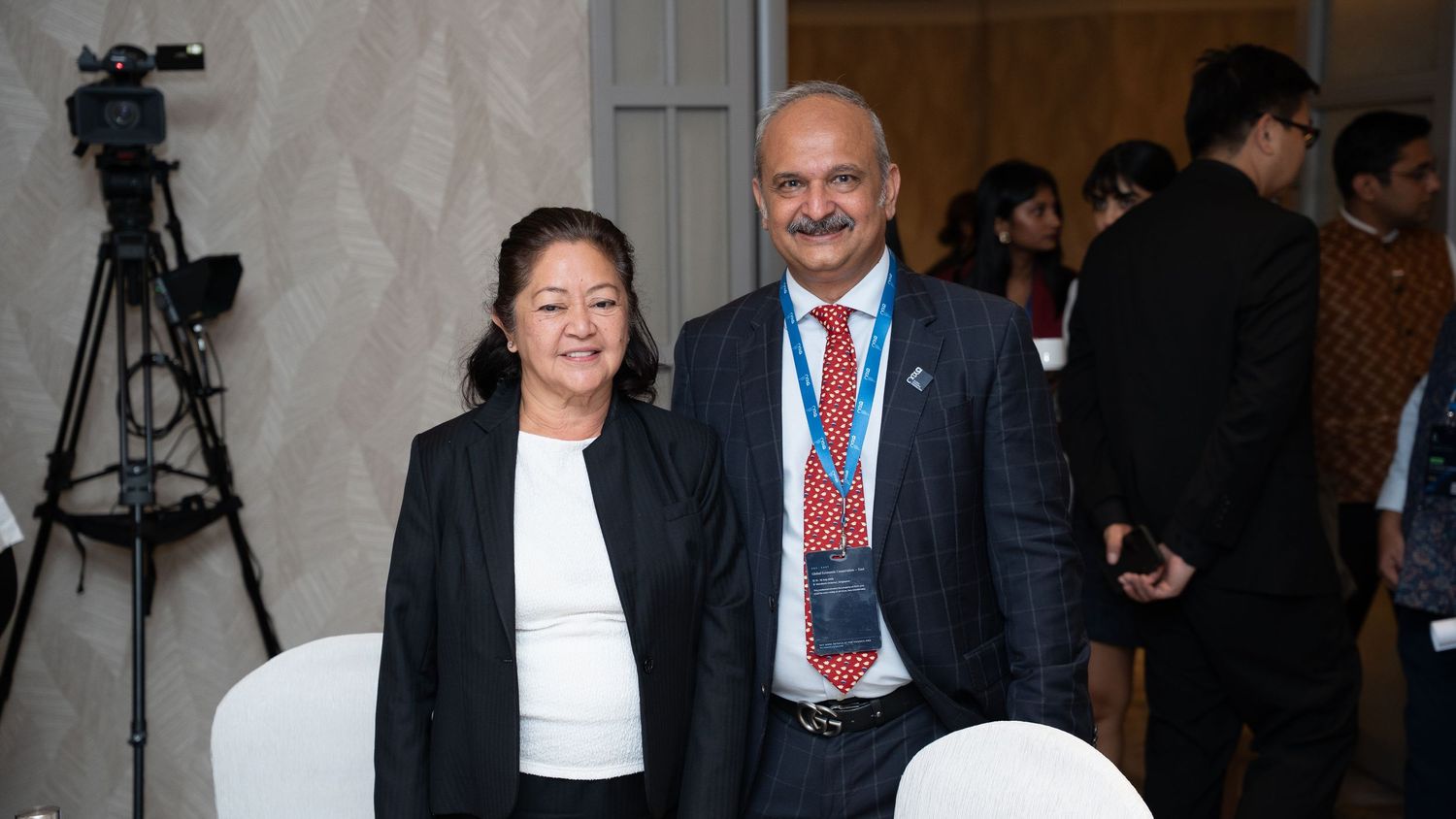 Two professionals pose together at an international conference event indoors.