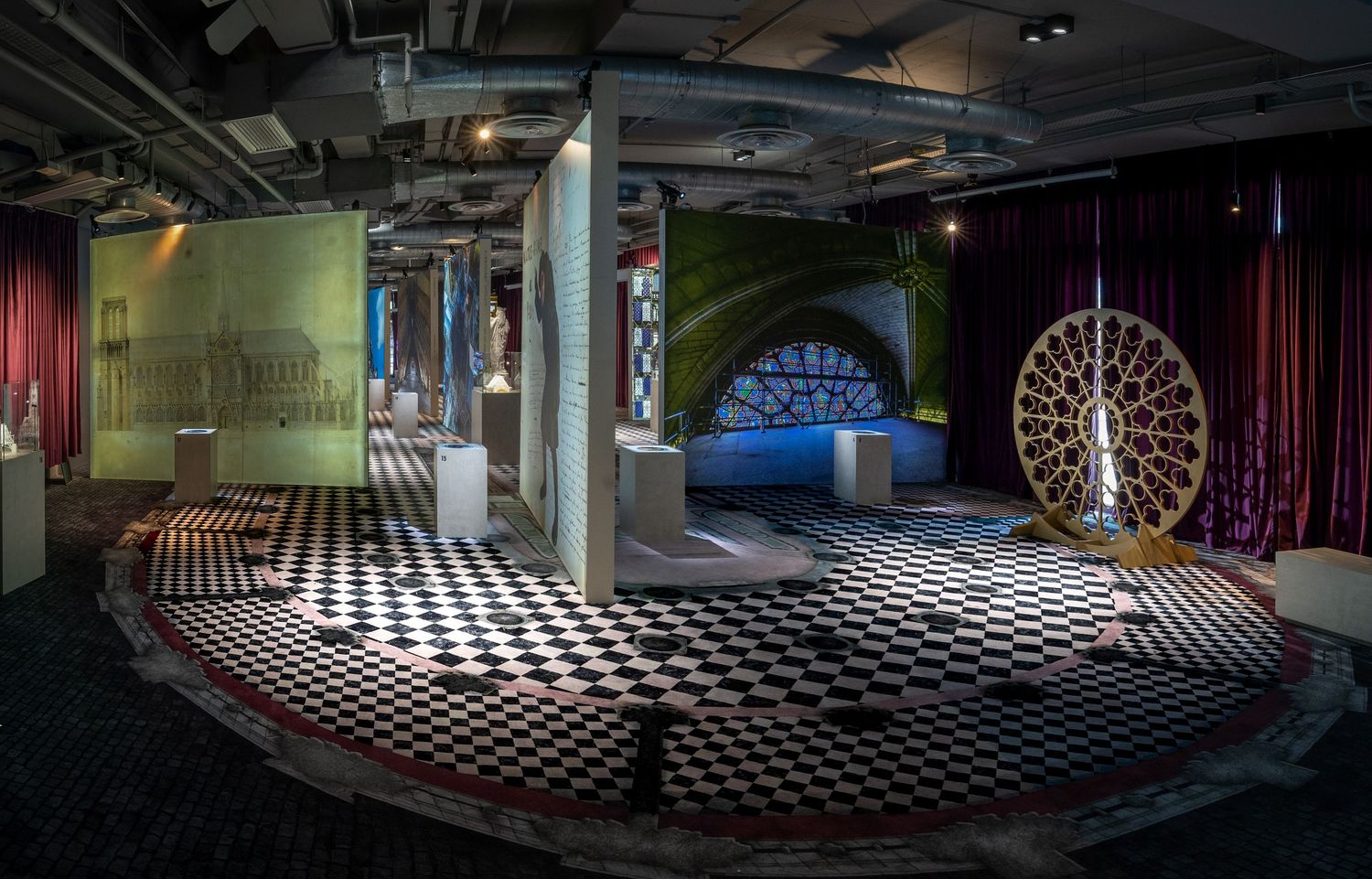 Immersive museum exhibit with checkered floor, colorful drapes, artistic installations, and dramatic lighting.