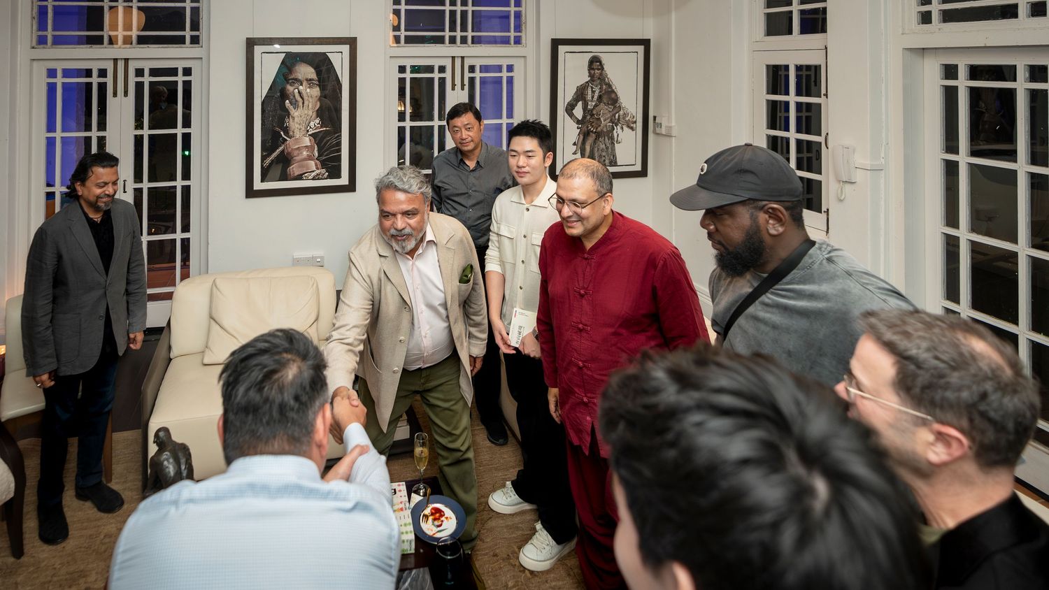 Group of men gathered in a warmly lit living room during an evening social gathering.