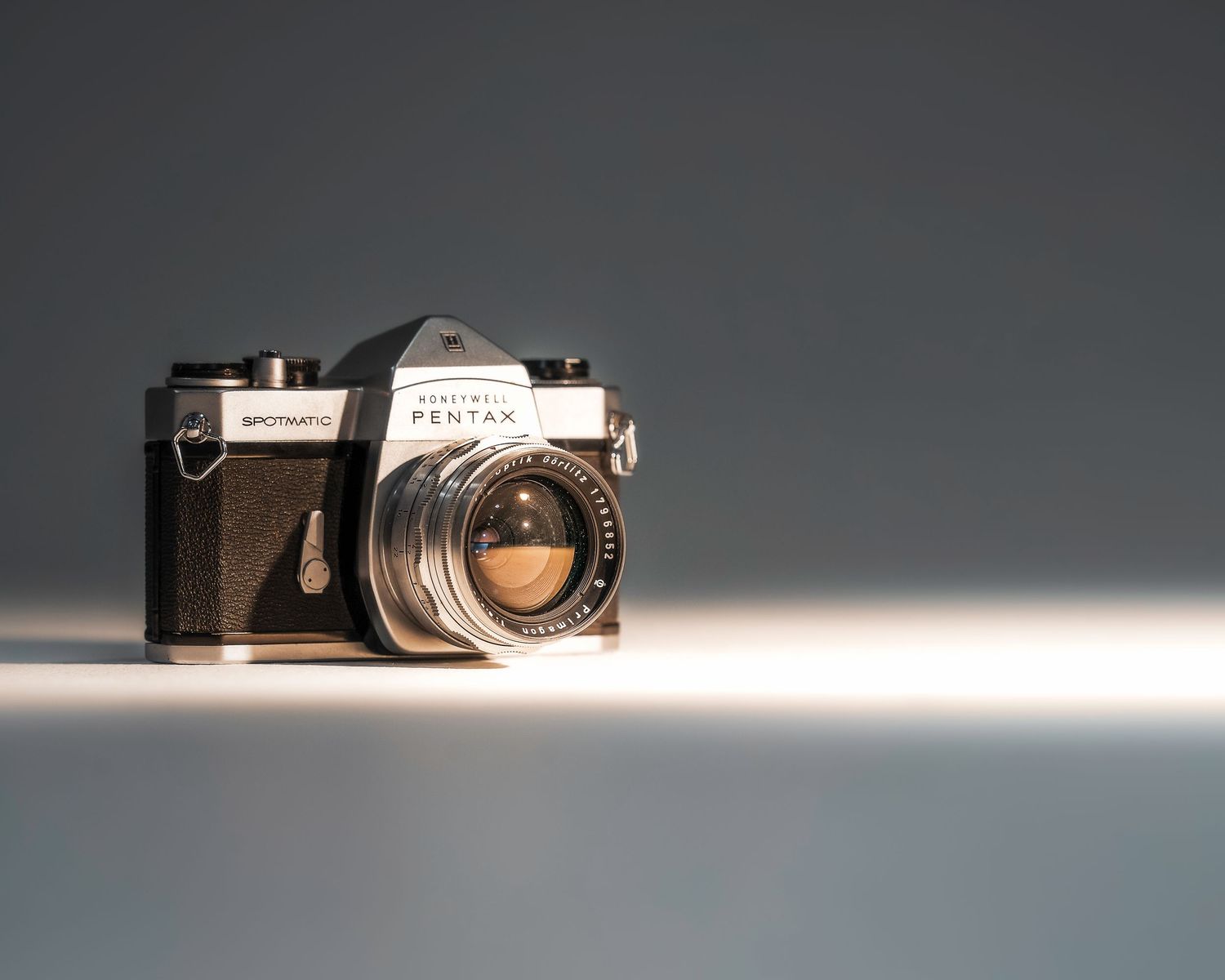 Vintage Pentax SLR film camera with chrome lens on a gray background, showcasing classic analog photography equipment.
