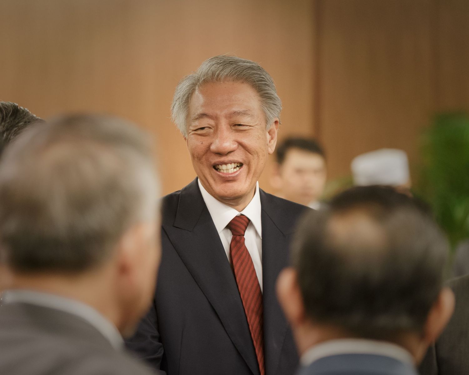 Smiling man in suit greeting guests at a formal networking event.