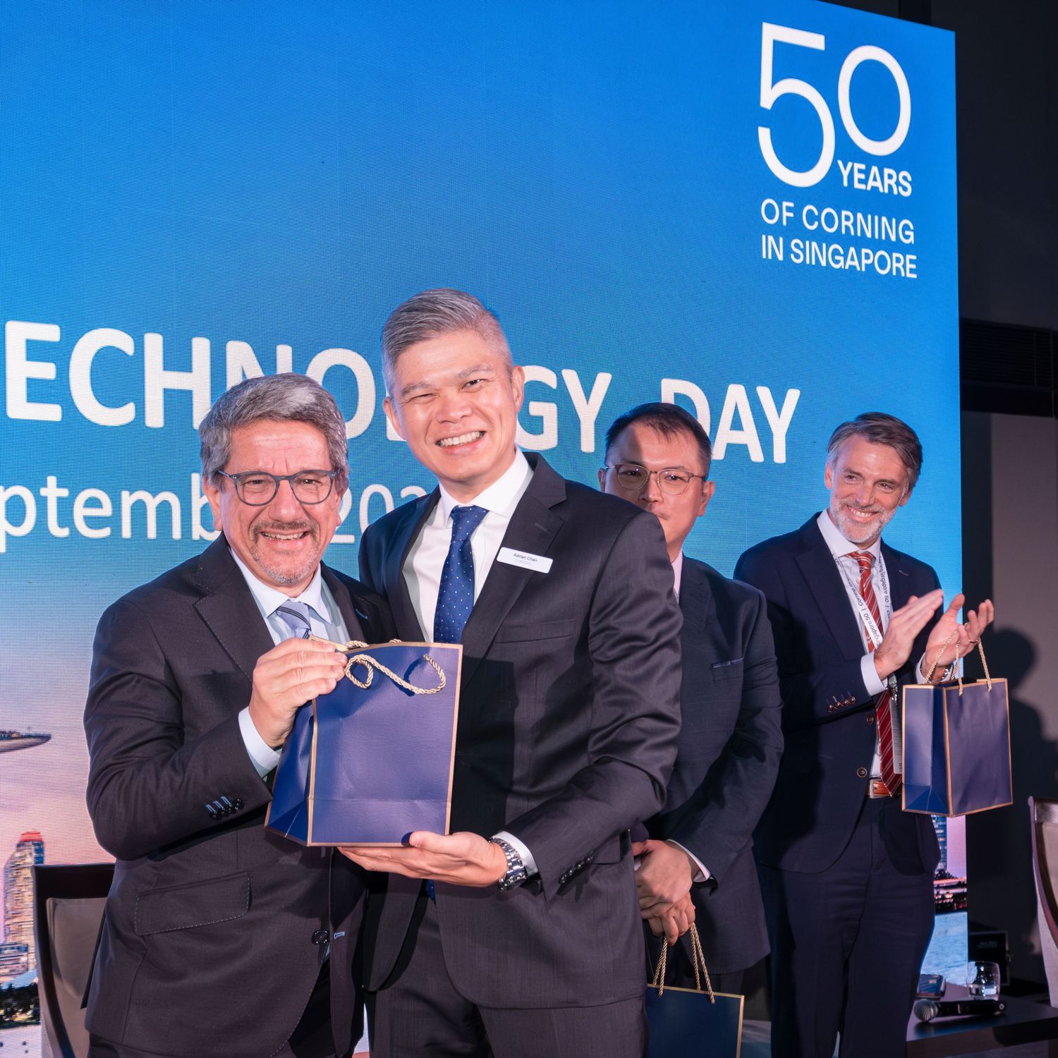 Two men exchange gifts at Corning Singapore 50th anniversary Technology Day corporate event.