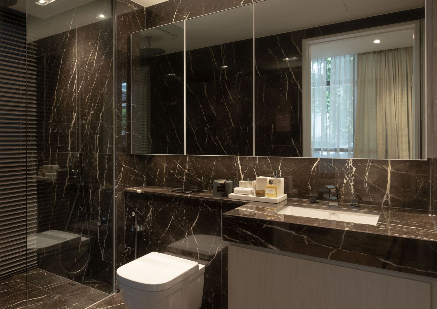 Luxurious bathroom featuring dark marble walls, glass shower, wall-mounted toilet, and elegant vanity with mirror.