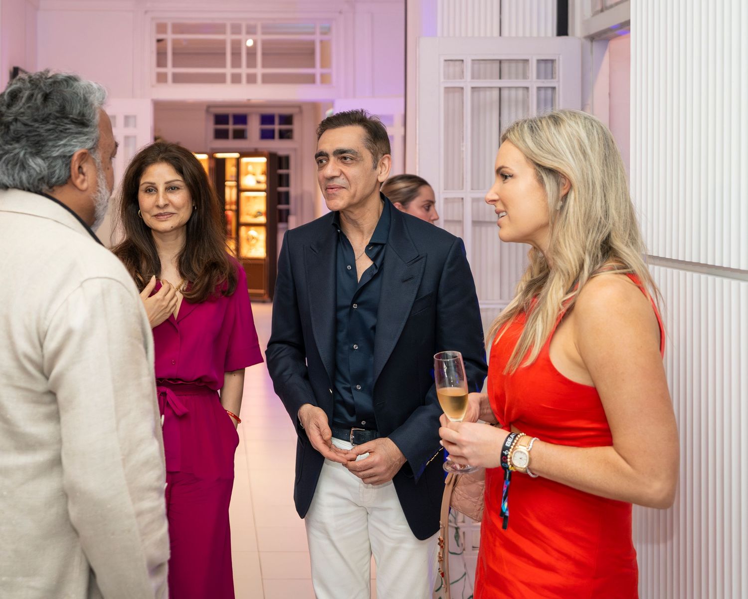 Elegantly dressed guests mingle and enjoy champagne at an upscale indoor social networking event.