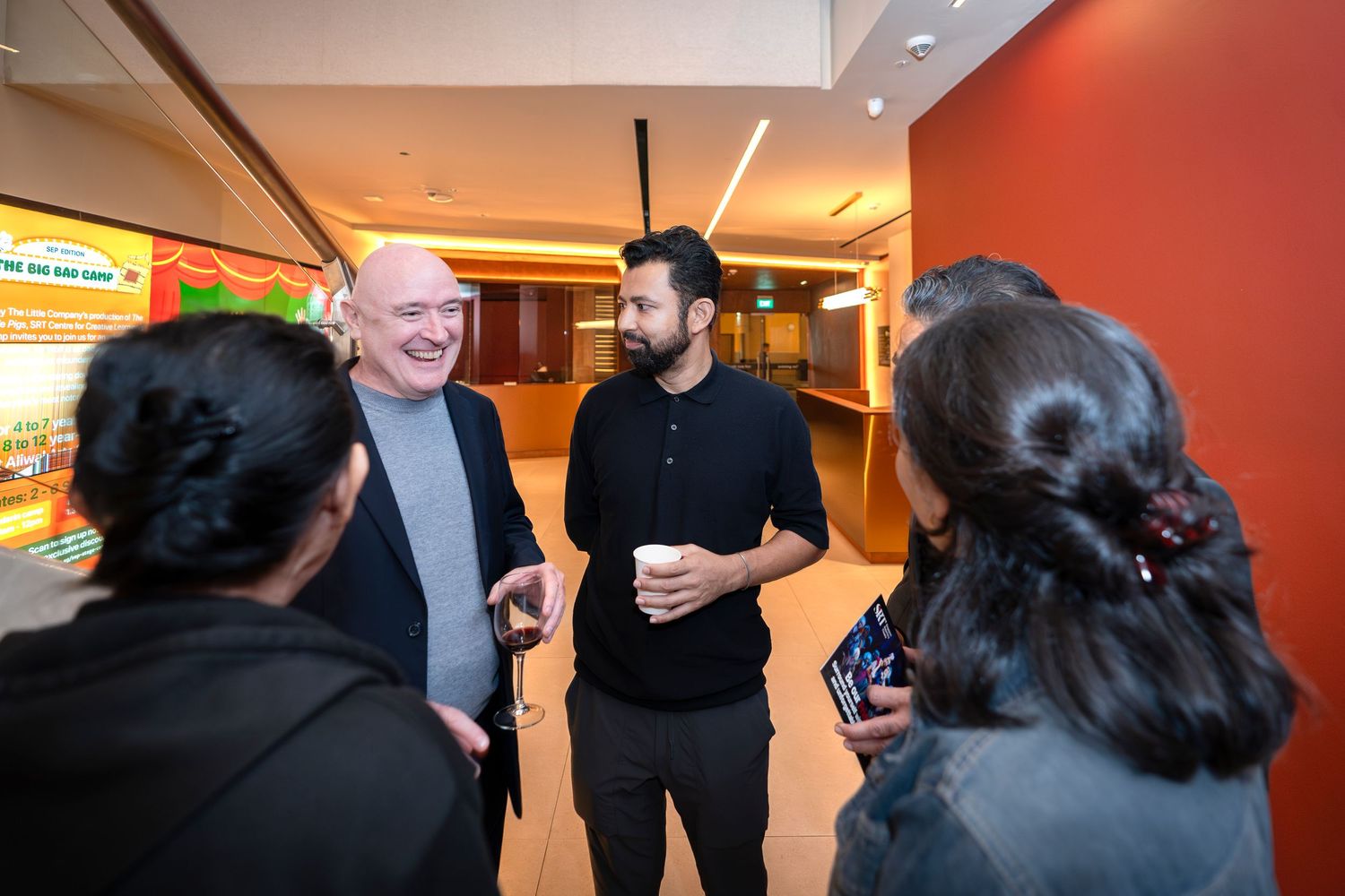 Group of professionals networking and conversing at an indoor corporate event reception.