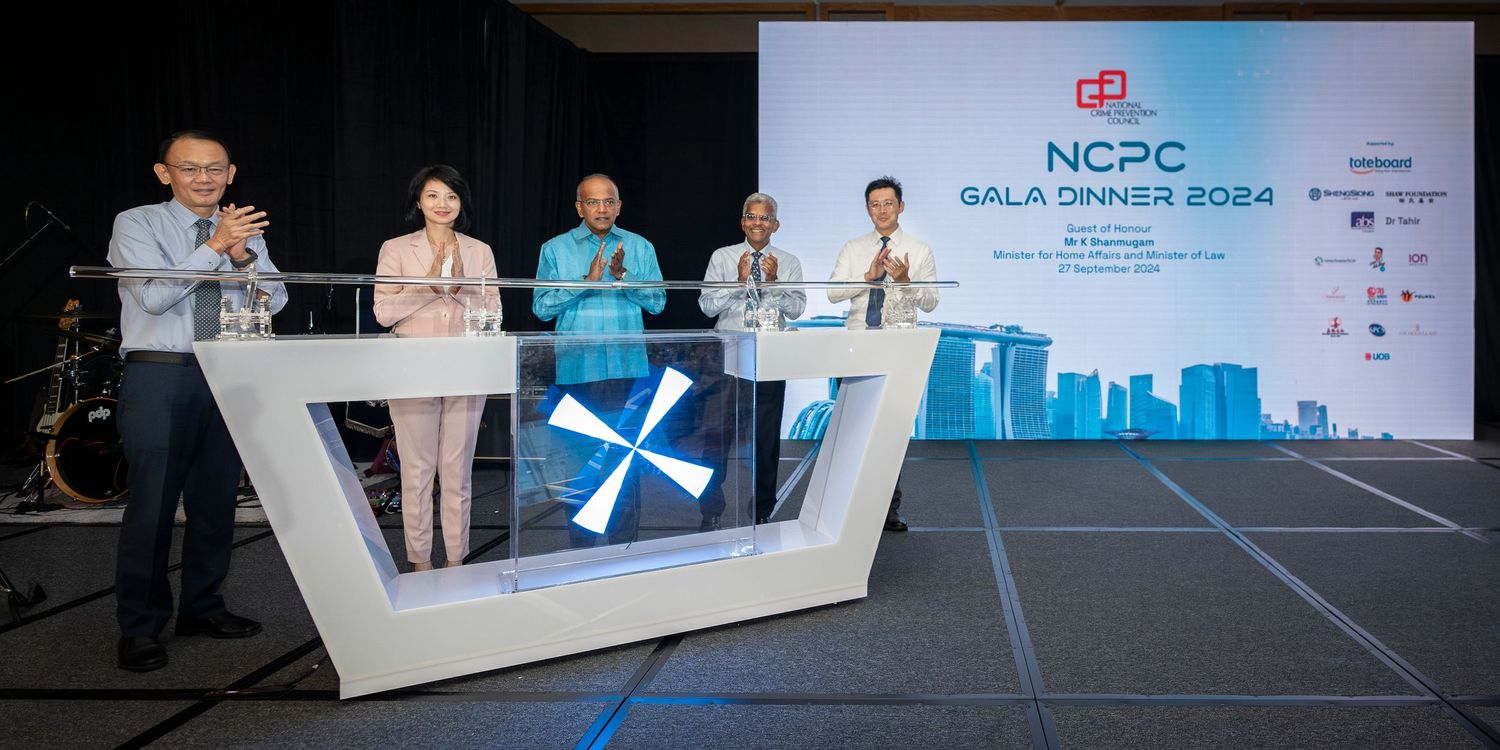 Speakers at NCPC Gala Dinner 2024 on stage with Singapore skyline backdrop at formal corporate event.