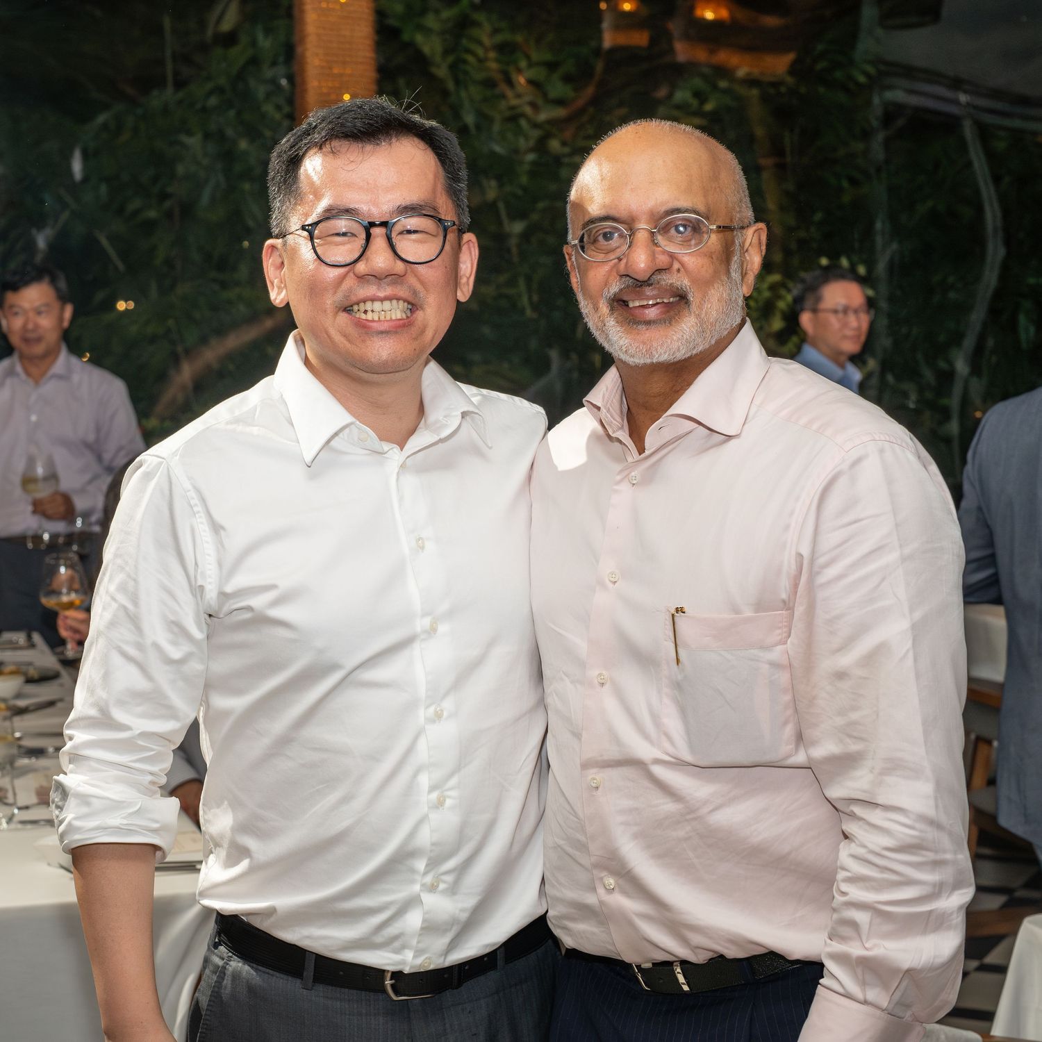 Two men sharing a friendly moment at an indoor social gathering, posing for a photo.