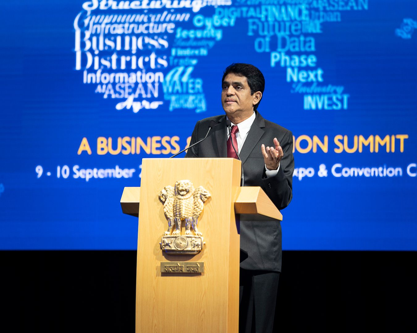 Indian official delivers speech at podium with national emblem at ASEAN Business Innovation Summit.
