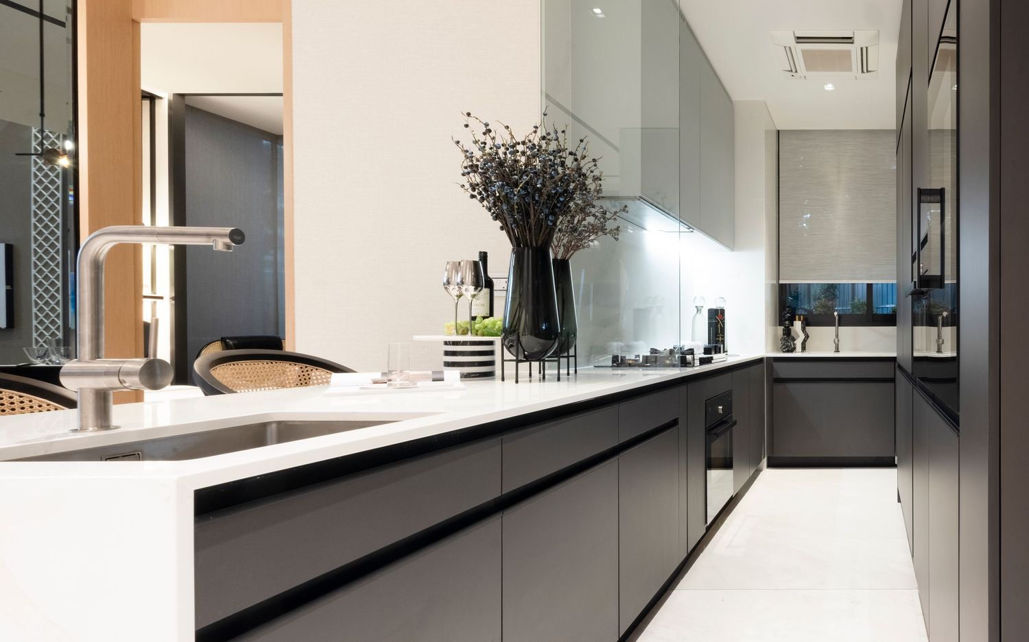 Sleek modern kitchen with dark cabinetry, white countertops, and minimalist design elements.