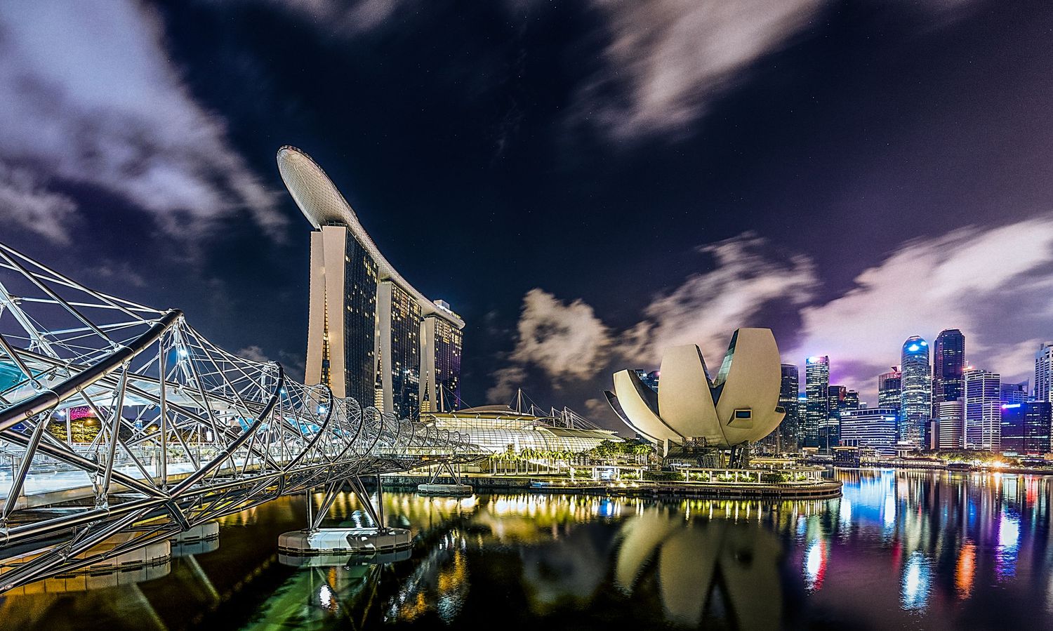 Singapore Marina Bay Sands hotel and ArtScience Museum reflecting in water at night with dramatic clouds.
