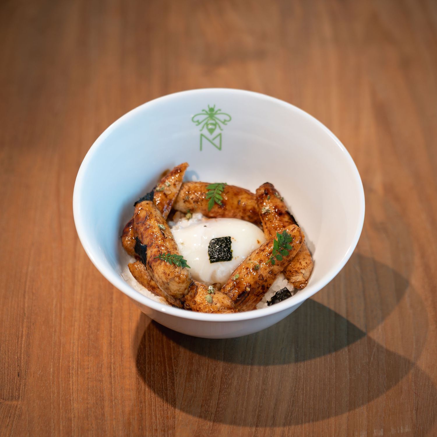 Gourmet bowl with crispy fried chicken, creamy white sauce, black caviar, and fresh herbs in a white ceramic bowl.