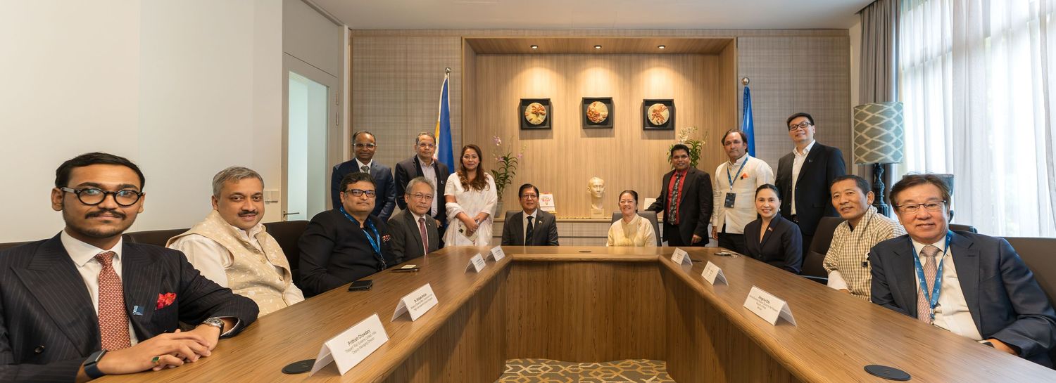 A diverse group of professionals poses for a formal group photo around a conference table indoors.