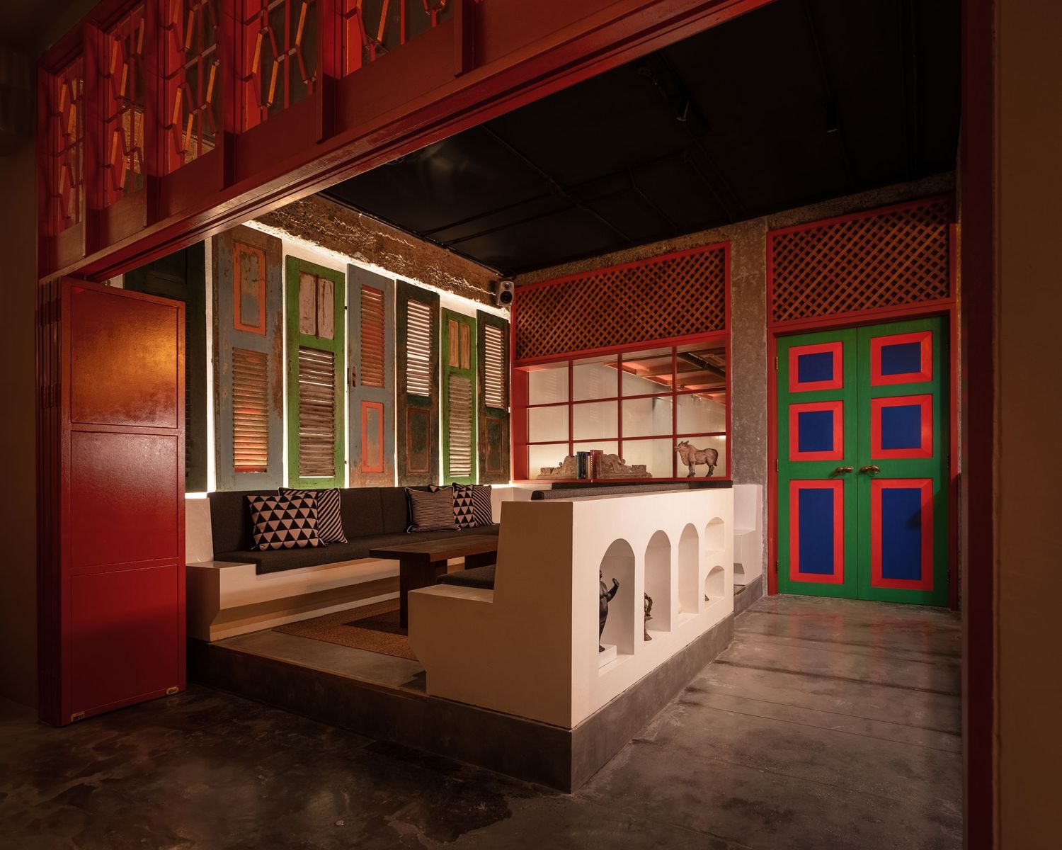 Vibrant Indian restaurant interior with colorful doors, red walls, arched bar counter, and traditional wooden shutters.