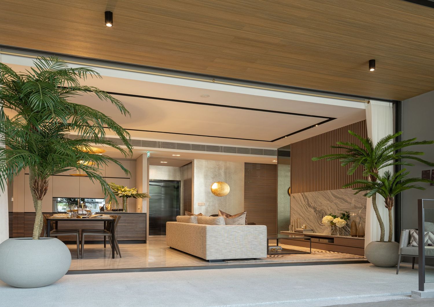 Modern open-plan living space with marble accents, tropical plants, and seamless indoor-outdoor design.