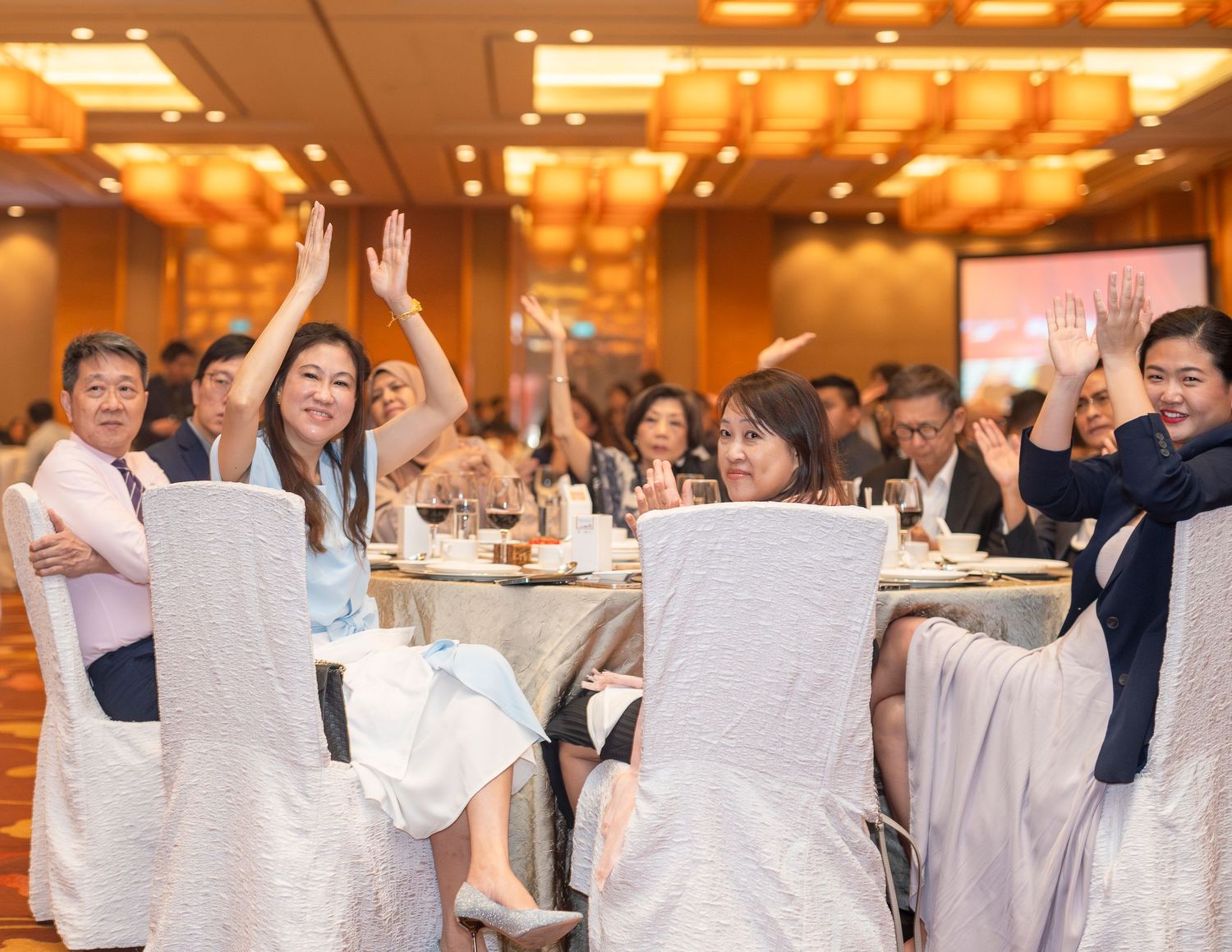 Guests raise hands in celebration at NCPC Gala Dinner 2024 banquet hall.