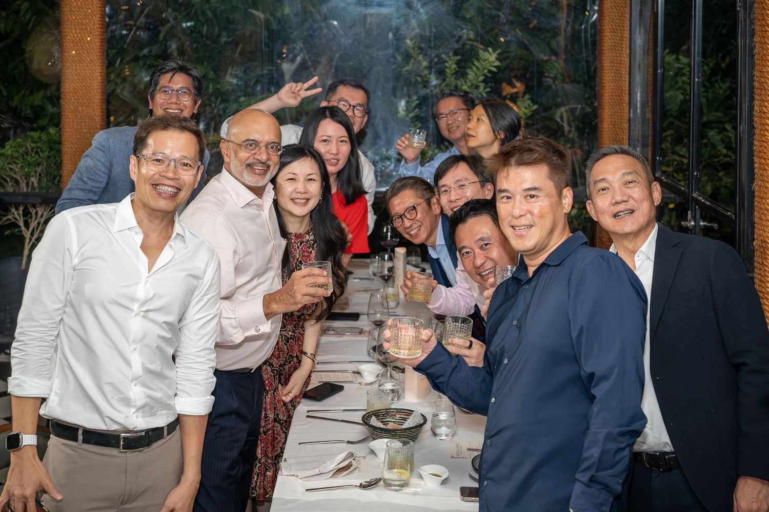 Group of smiling friends toasting with wine glasses at a restaurant dinner gathering.