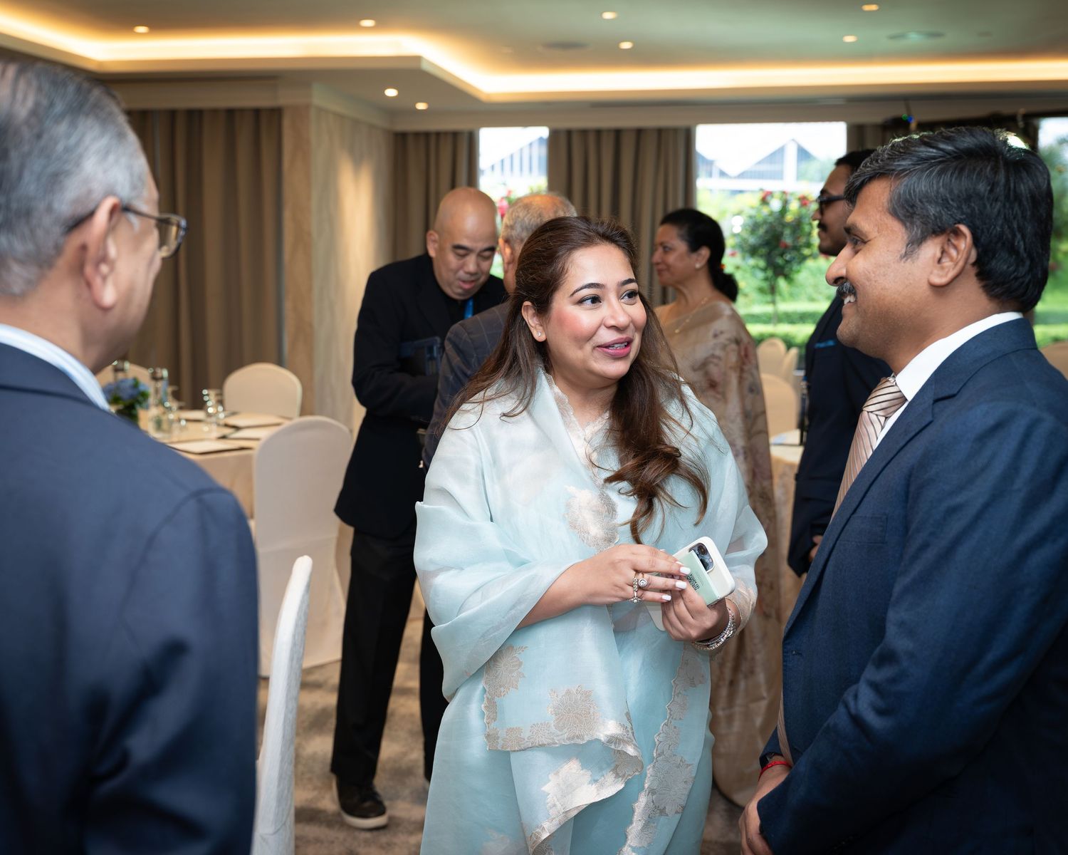 Professionals networking at a formal indoor event, smiling and conversing in an elegantly set dining room.