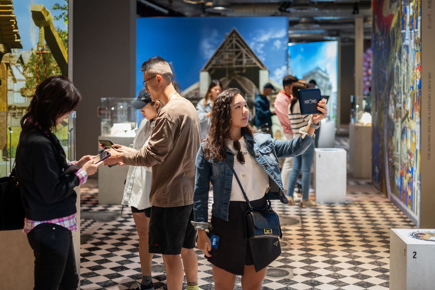 Visitors exploring a colorful museum exhibit while taking photos with smartphones.