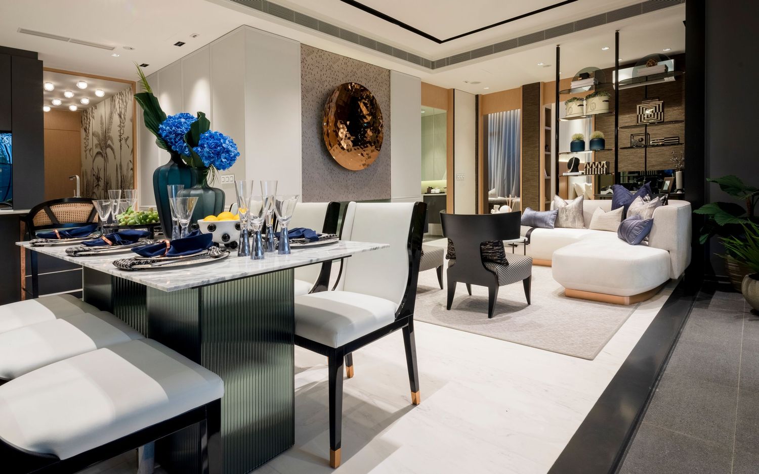Sophisticated open-plan dining and living room with dark table, blue flowers, and modern decor.