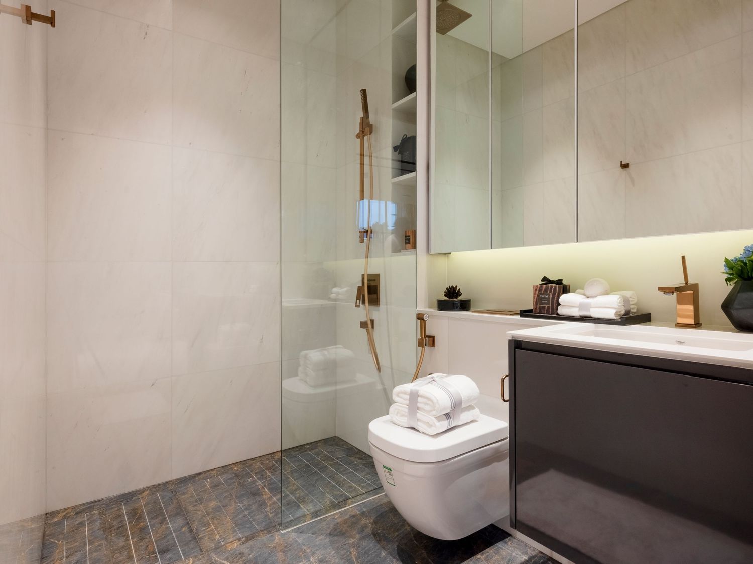 Modern bathroom with walk-in shower, wall-hung toilet, and marble vanity.