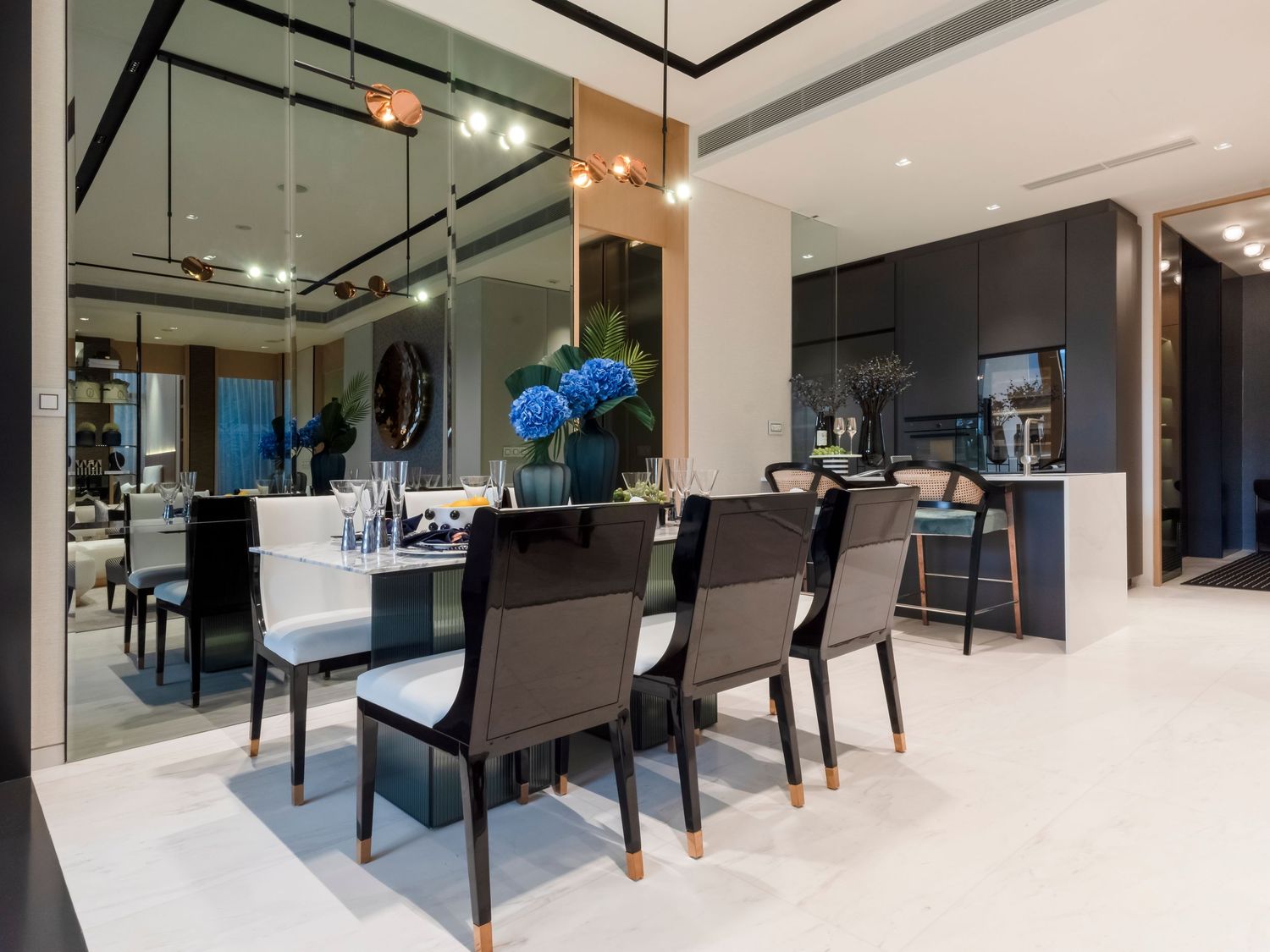 Stylish modern dining room with black chairs, marble table, blue flowers, and mirrored walls.