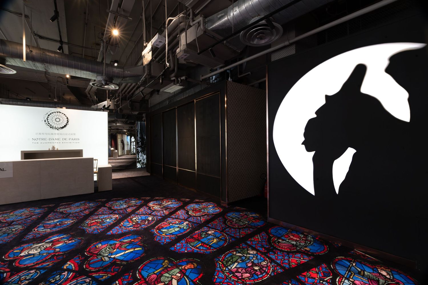 Unique event space with colorful stained glass carpet, black walls, and a dramatic cat silhouette mural.