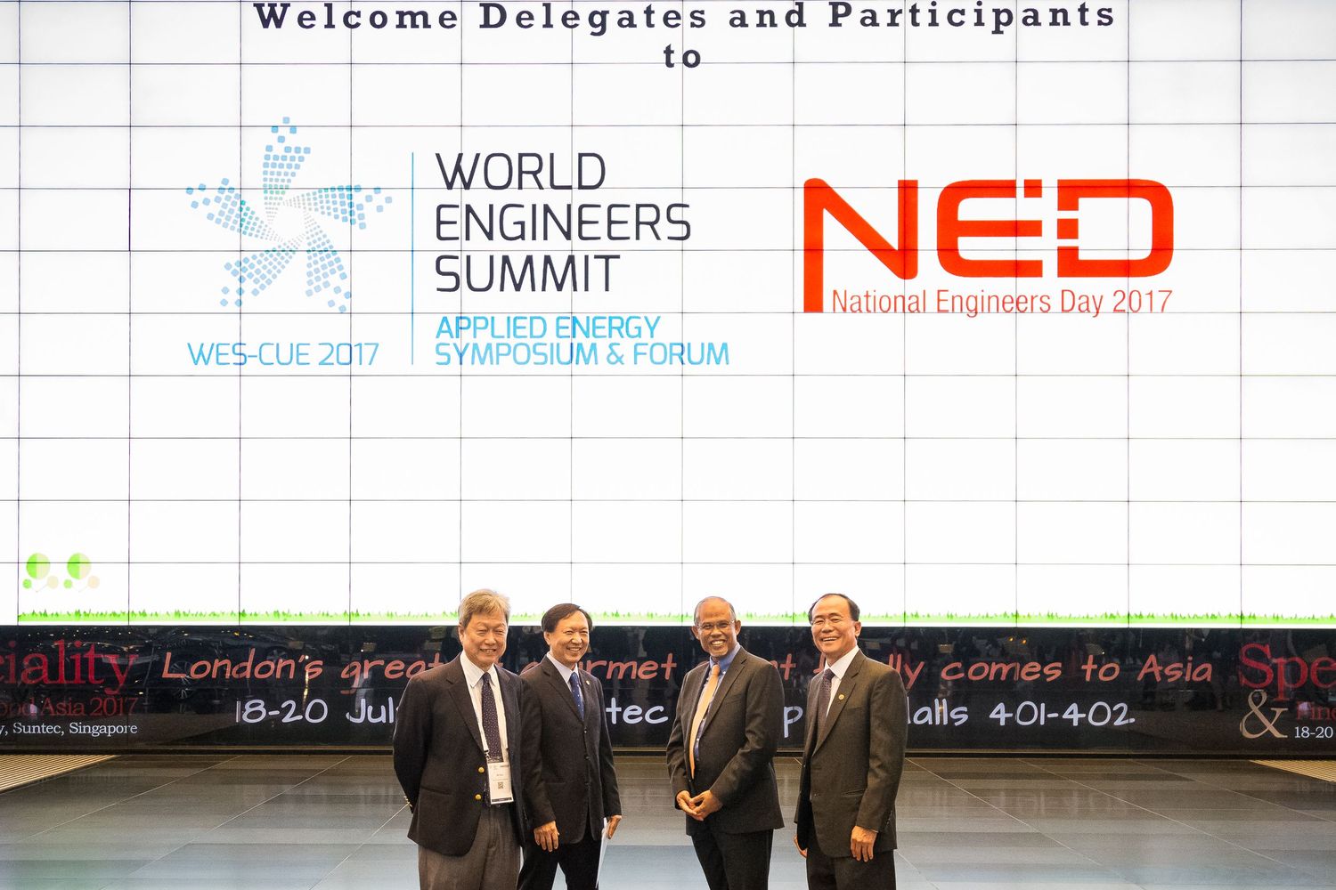 Four professionals pose at the World Engineers Summit Applied Energy Symposium and Forum alongside National Engineers Day 2017 signage.
