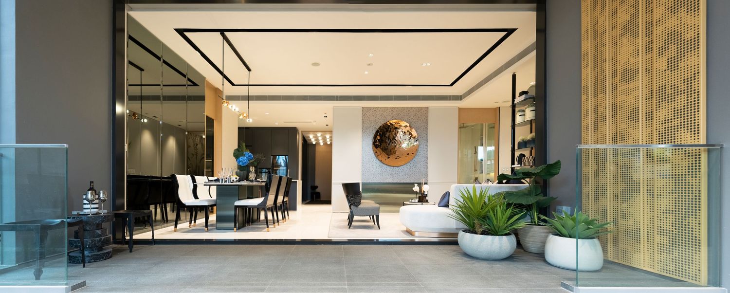 Modern luxury living space viewed through glass doors with elegant furniture and indoor plants.