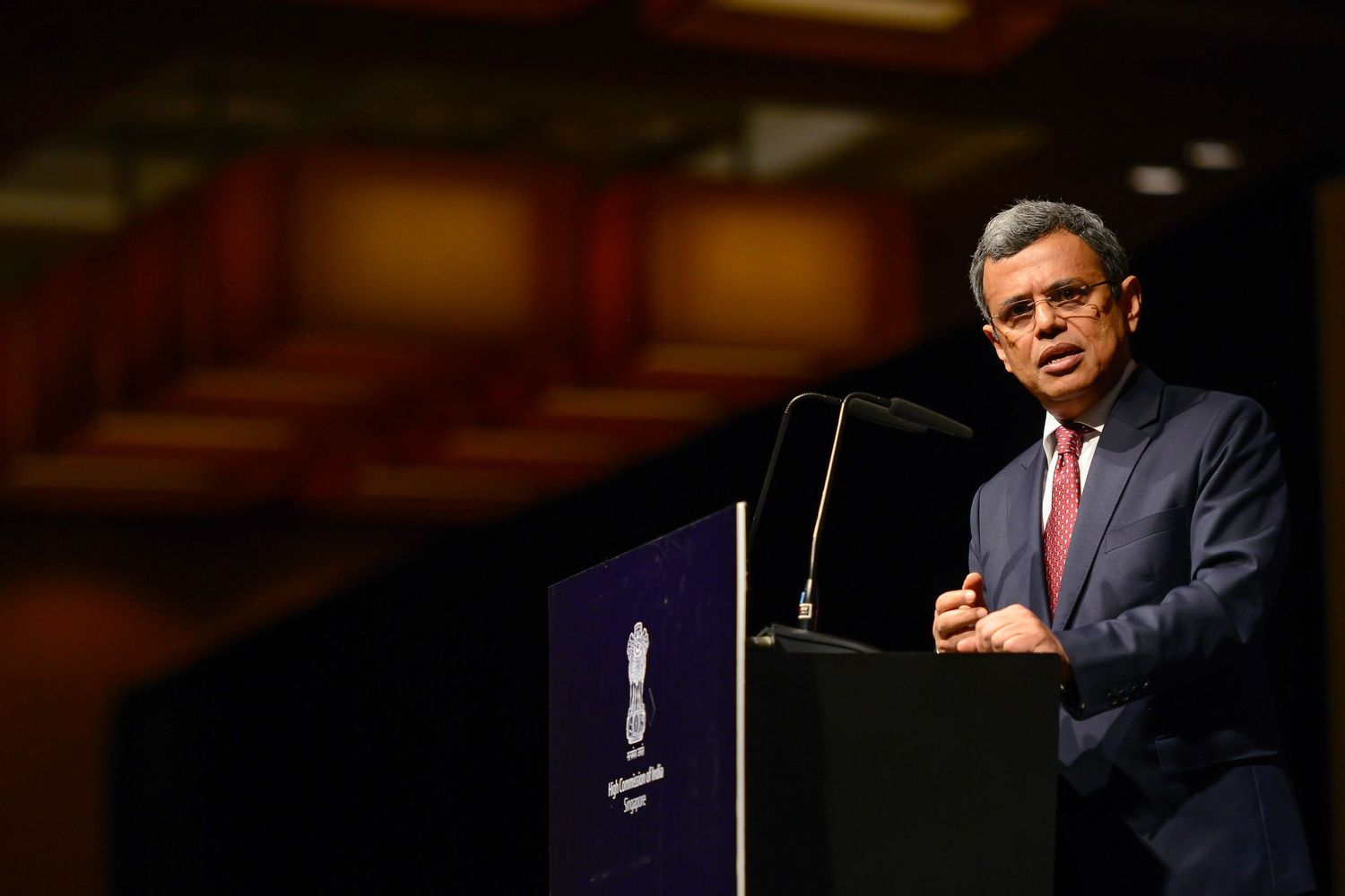 Professional speaker at podium delivering keynote address at formal conference event.
