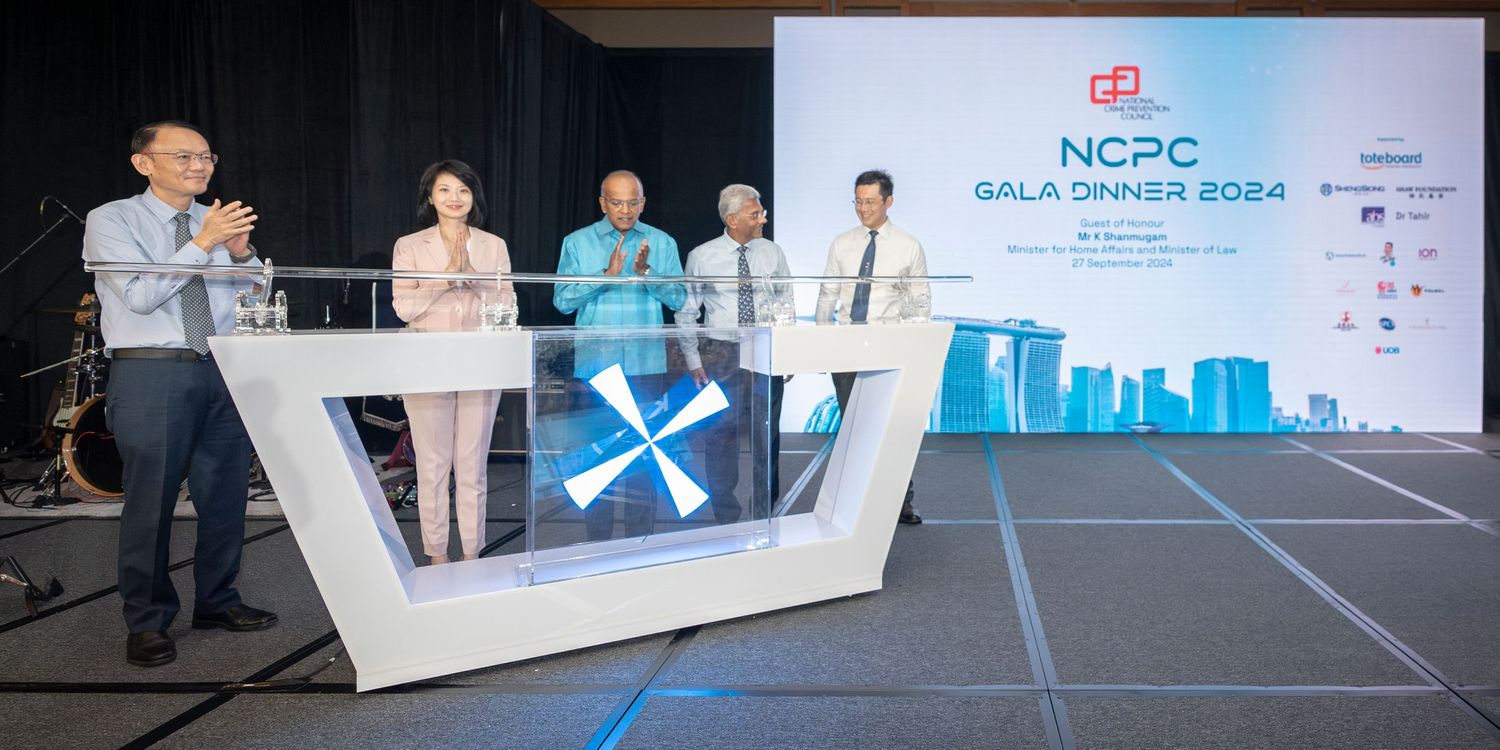 NCPC Gala Dinner 2024 ceremony with four people on stage at podium with city skyline backdrop.
