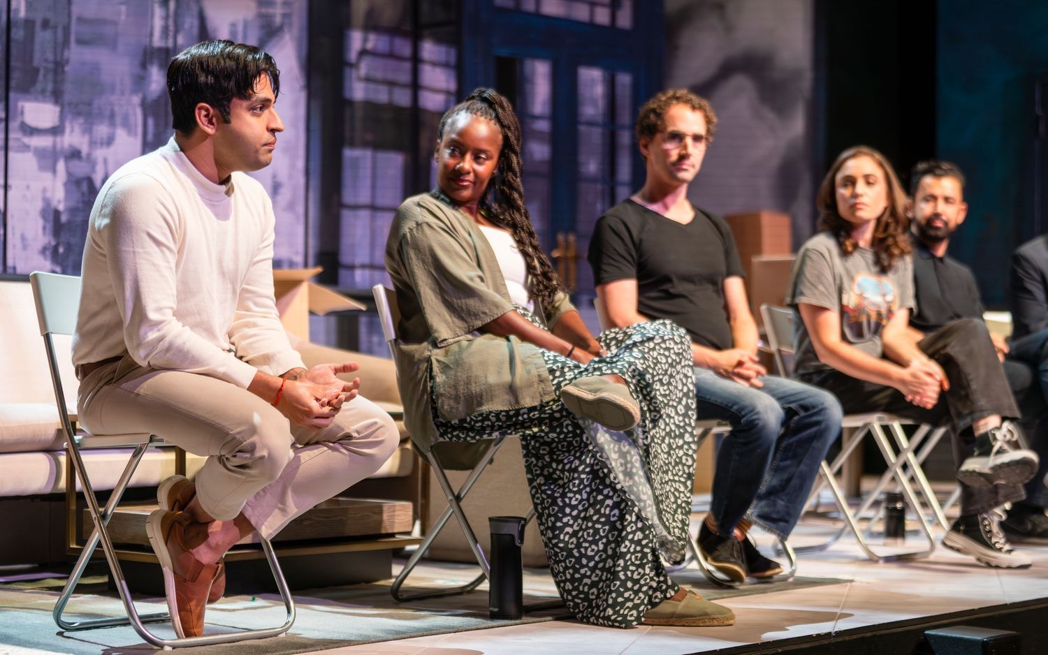 Five diverse panelists seated on stage during a theater or conference discussion event.
